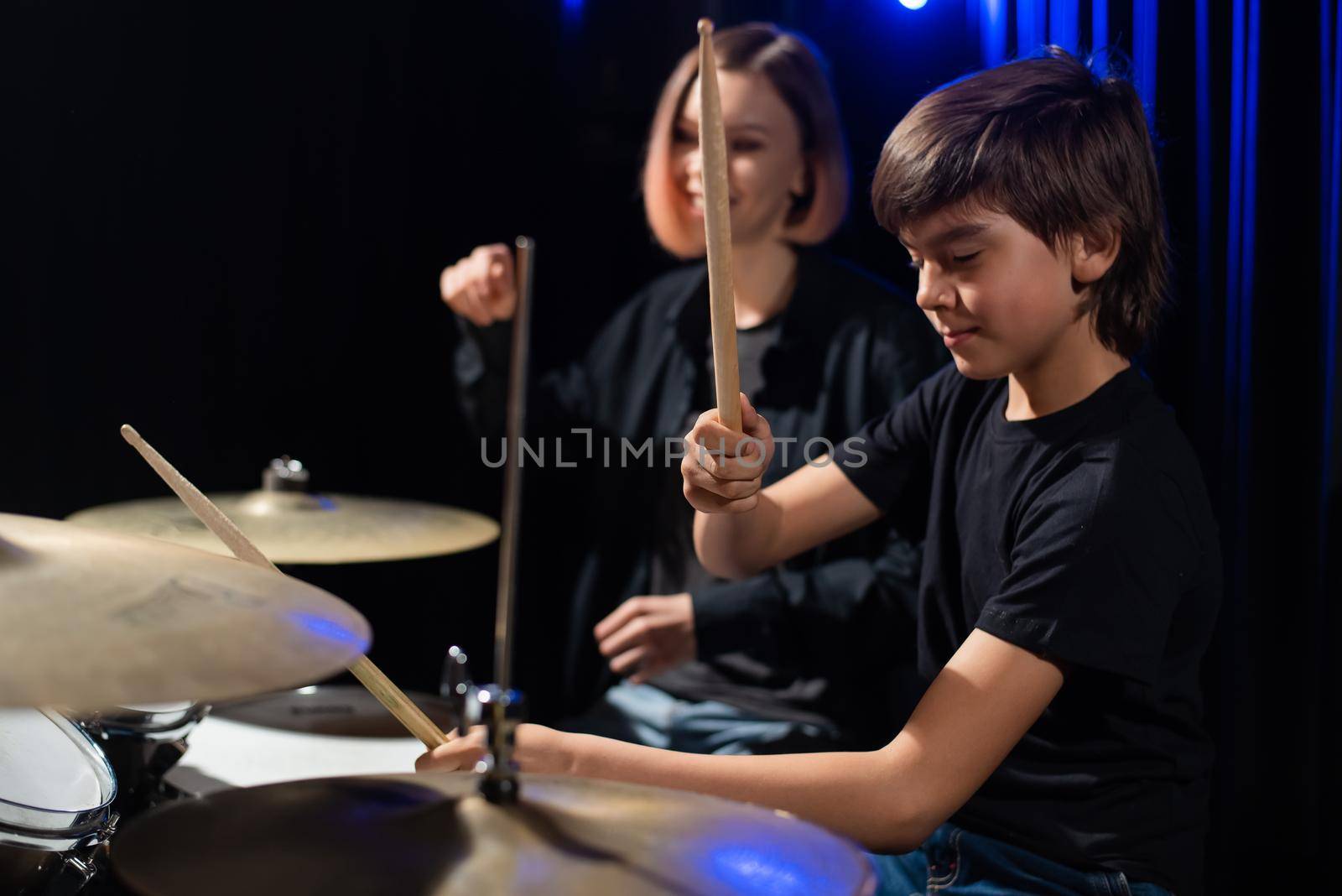 Young woman teaching boy to play drums. by mrwed54