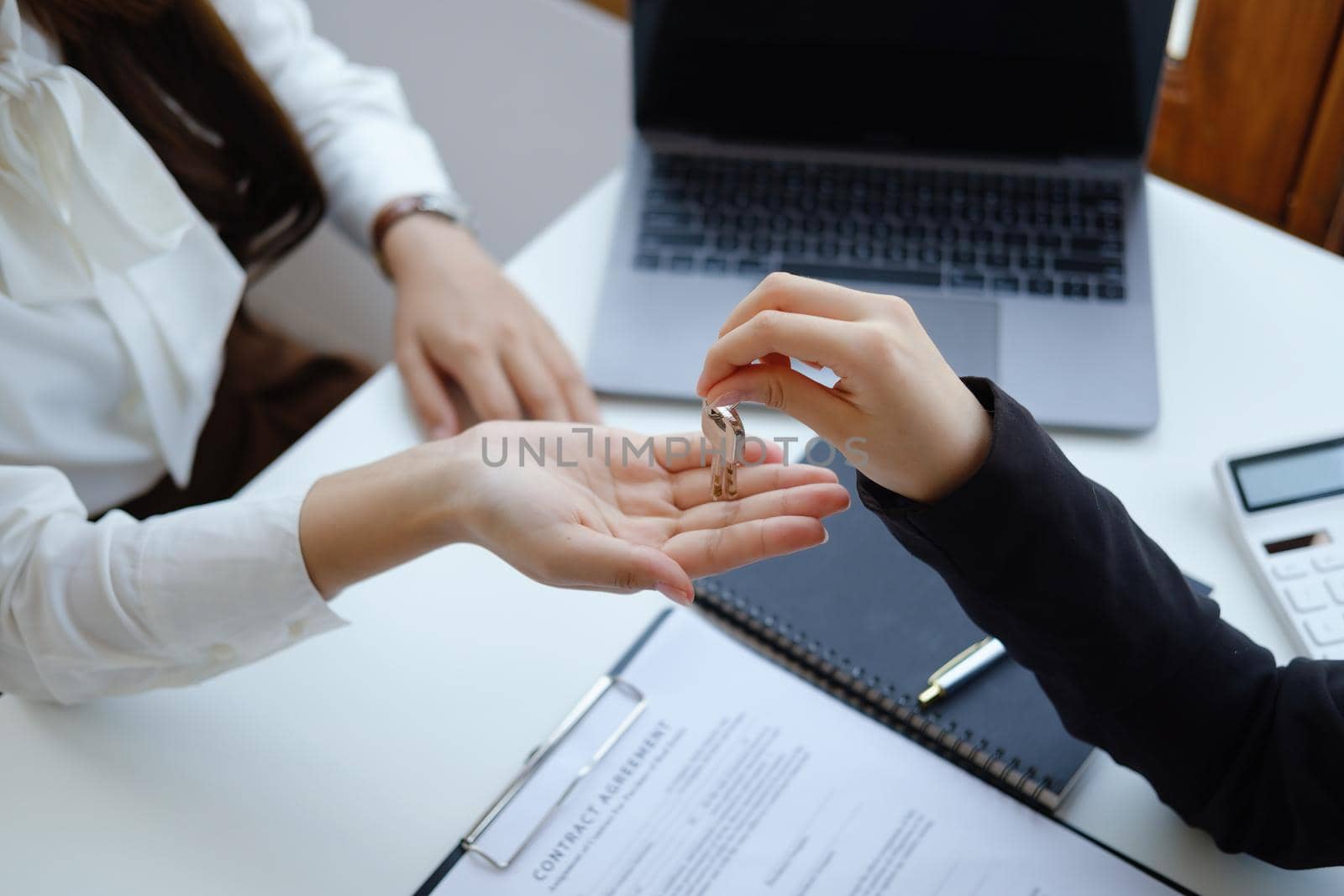 Accountant, businessman, real estate agent, Asian business woman handing keys to customers along with house after customers to sign by Manastrong