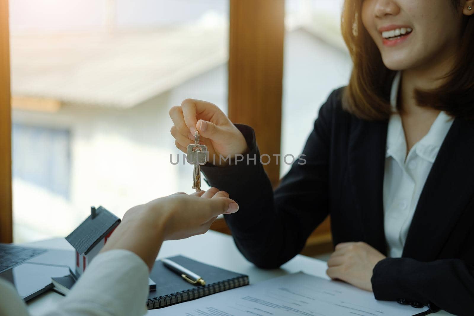 Accountant, businessman, real estate agent, Asian business woman handing keys to customers along with house after customers to sign.