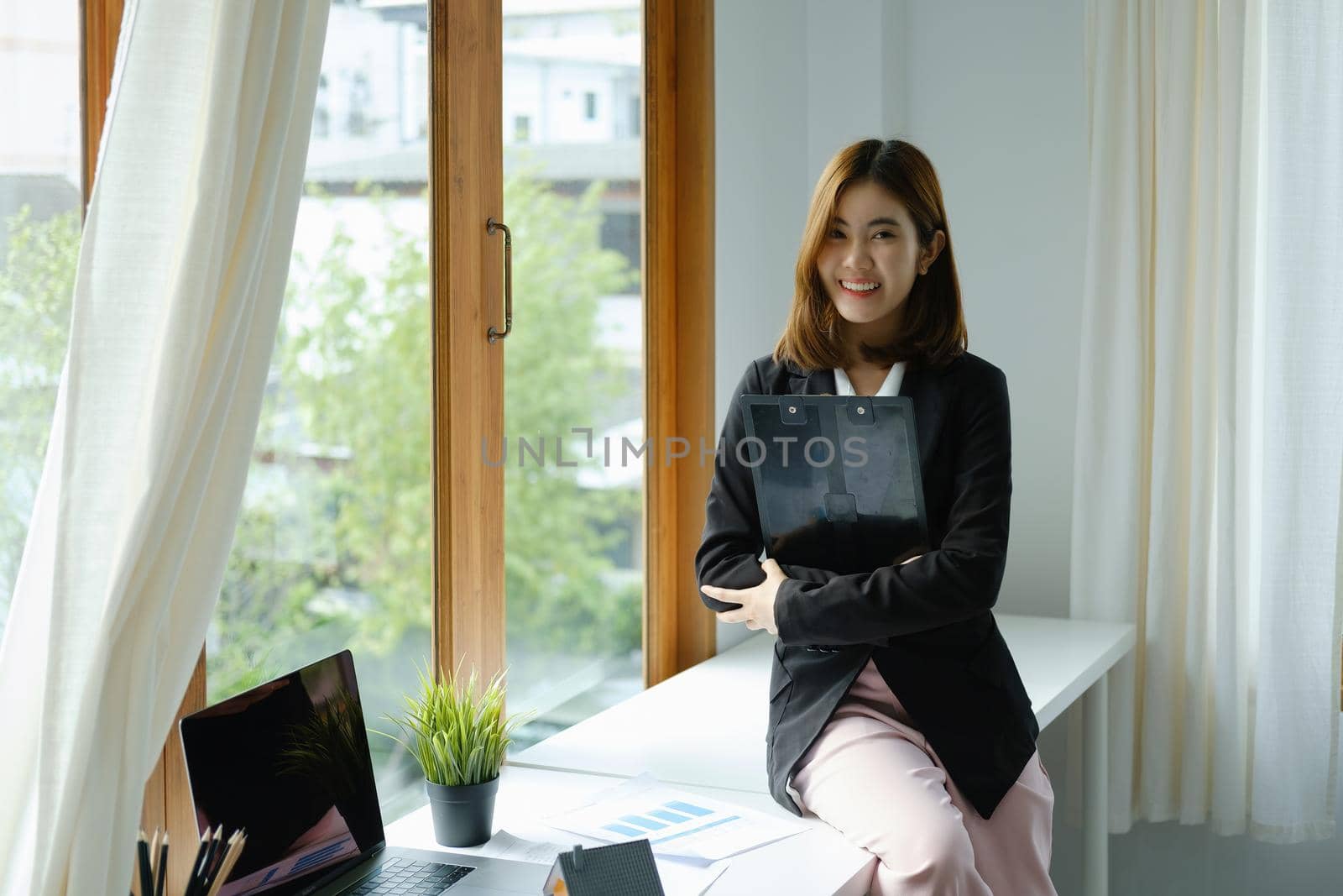 Portrait of a smiling Asian businesswoman holding job analysis and financial and marketing documents.