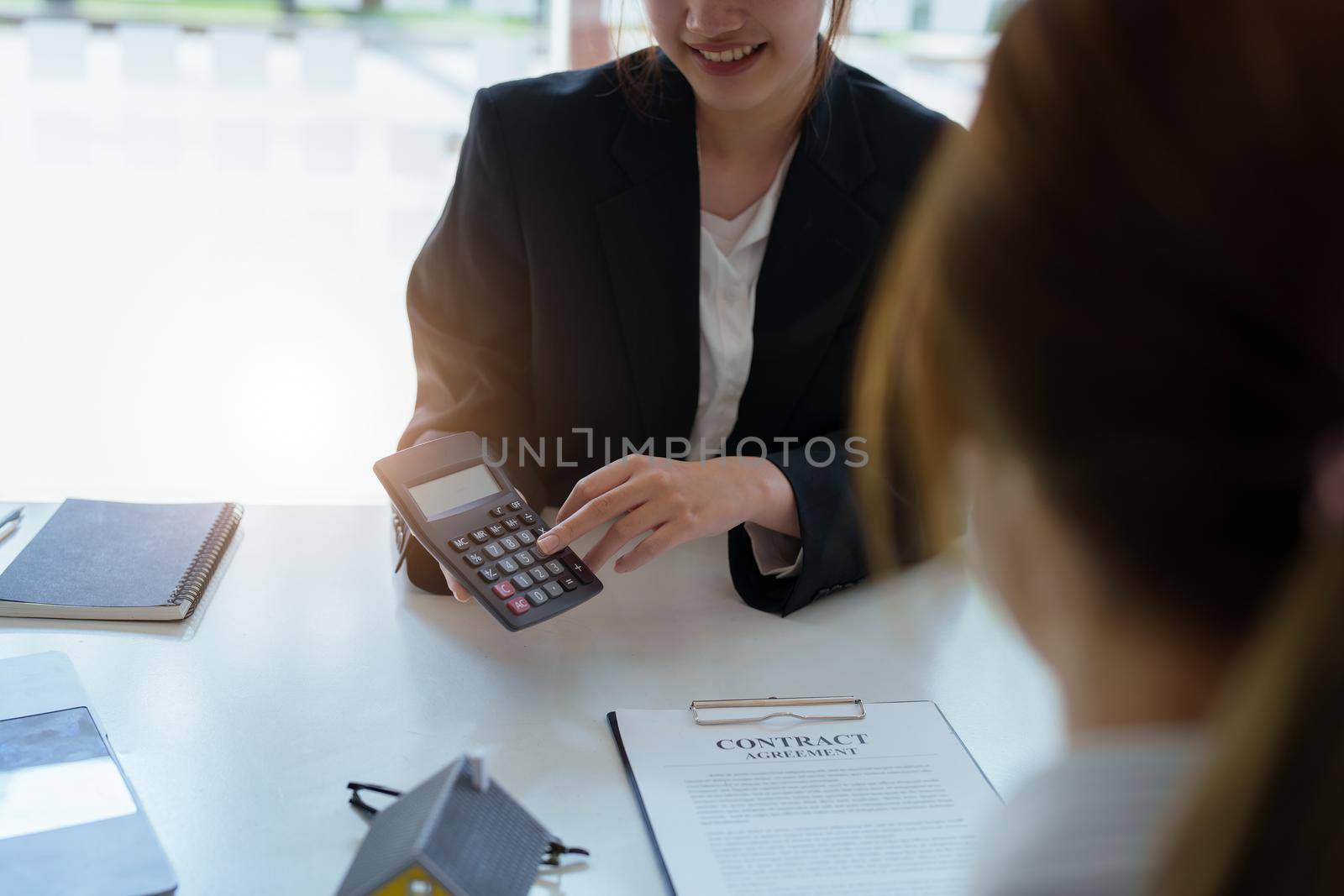 Guarantee, mortgage, contract, contract, signed, real estate agent or bank officer holding a calculator, submits a bid with a customer to buy a home before signing to make a deal by Manastrong