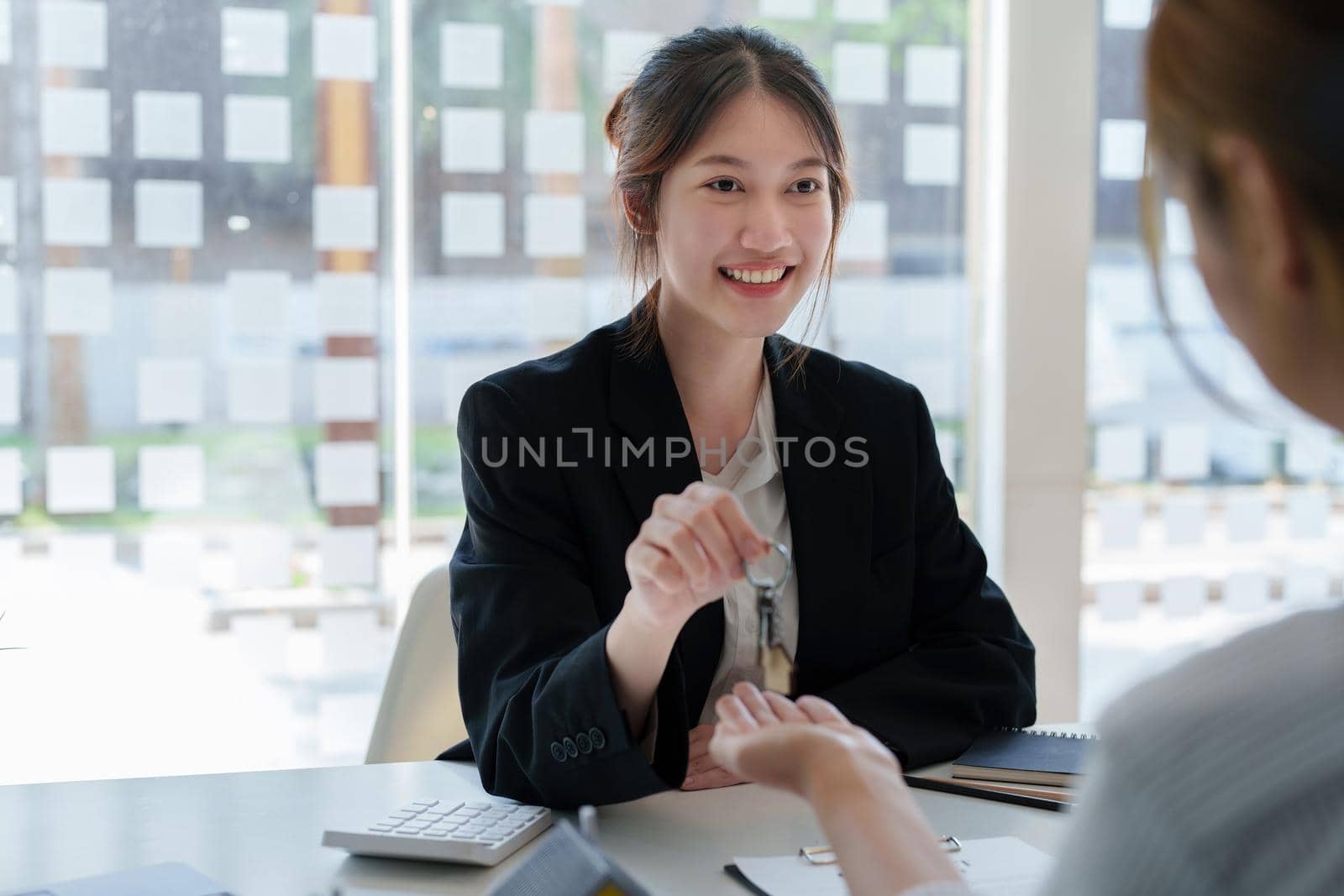 Accountant, businessman, real estate agent, Asian business woman handing keys to customers along with house after customers to sign.