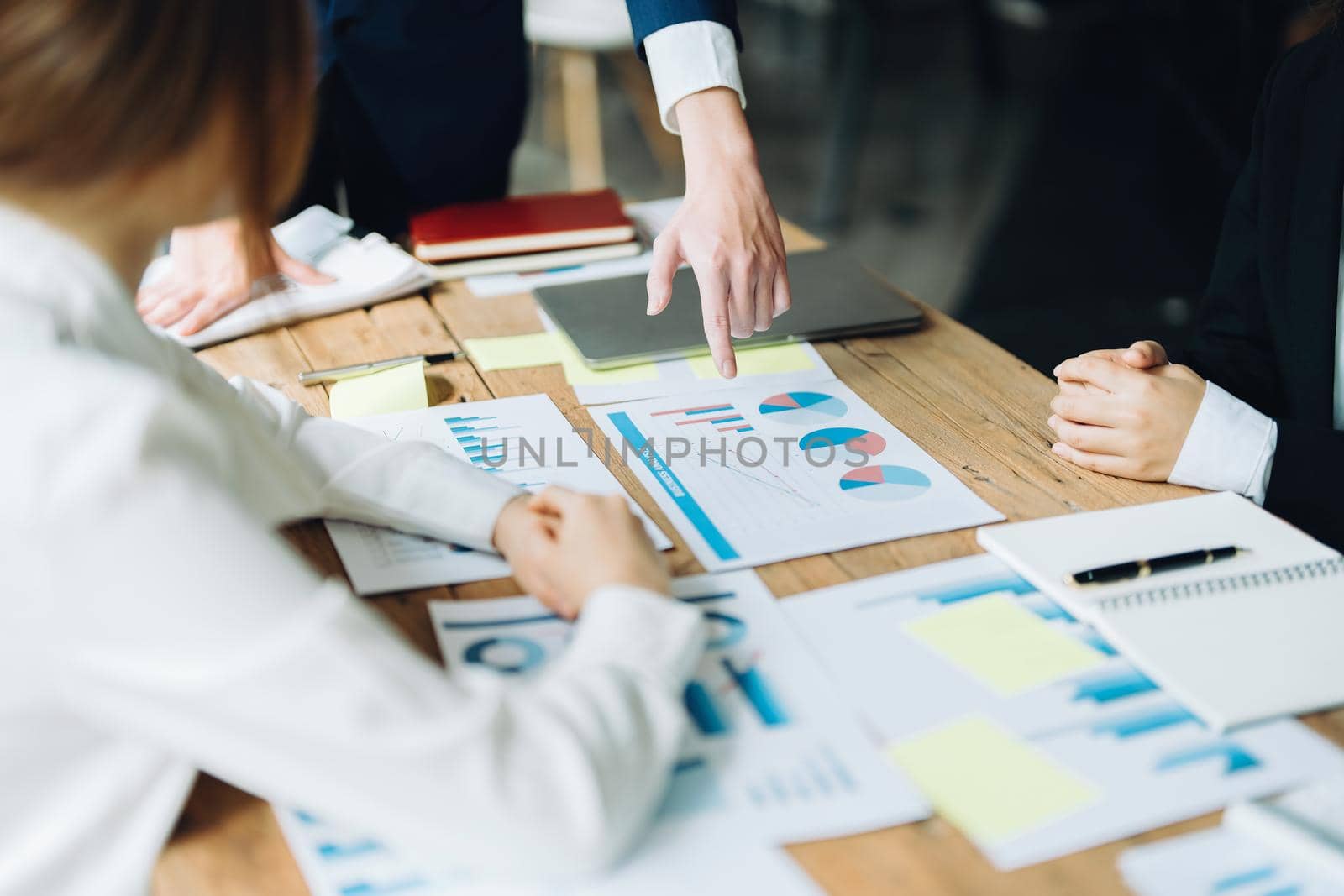Male businessman pointing to documents summarizing marketing strategy with female colleagues in meeting, teamwork, investment planning.