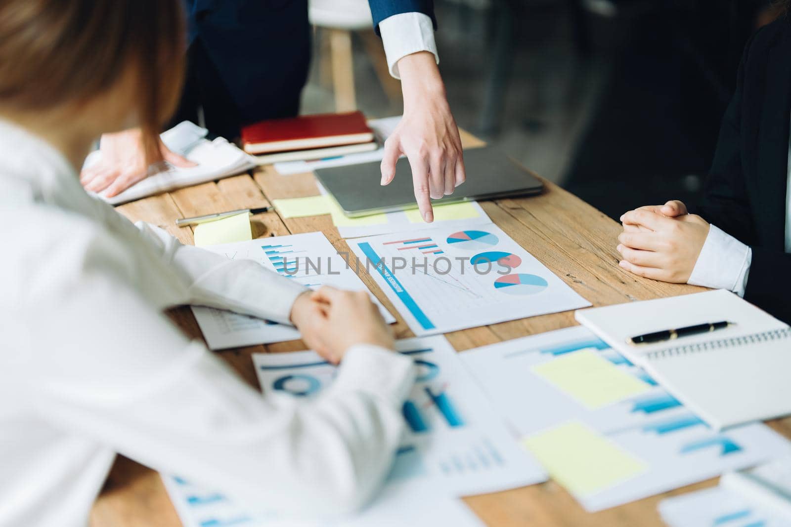 Male businessman pointing to documents summarizing marketing strategy with female colleagues in meeting, teamwork, investment planning by Manastrong