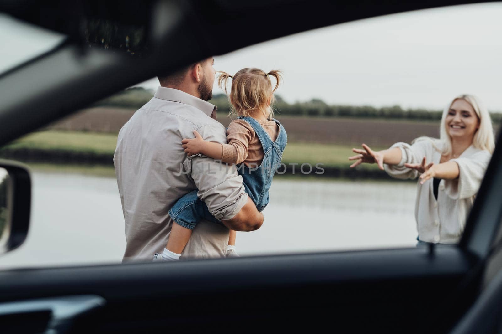 View Through Window Inside of Car, Happy Young Family with Kid Together Enjoying Weekend Outside the City by Romvy