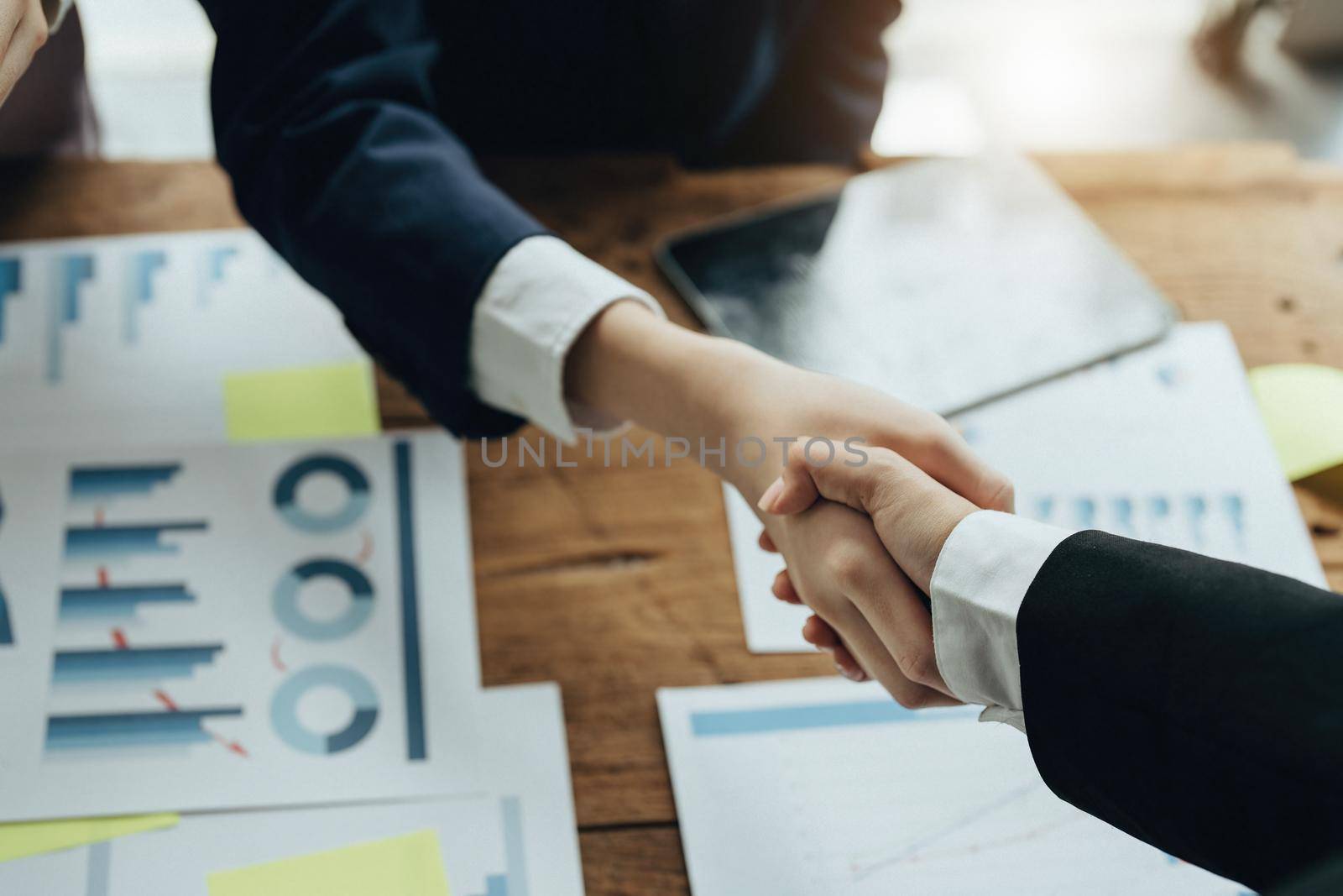 Asian entrepreneurs handshakes to congratulate the agreement between the two companies to enhance investment and financial strength. deal concept by Manastrong