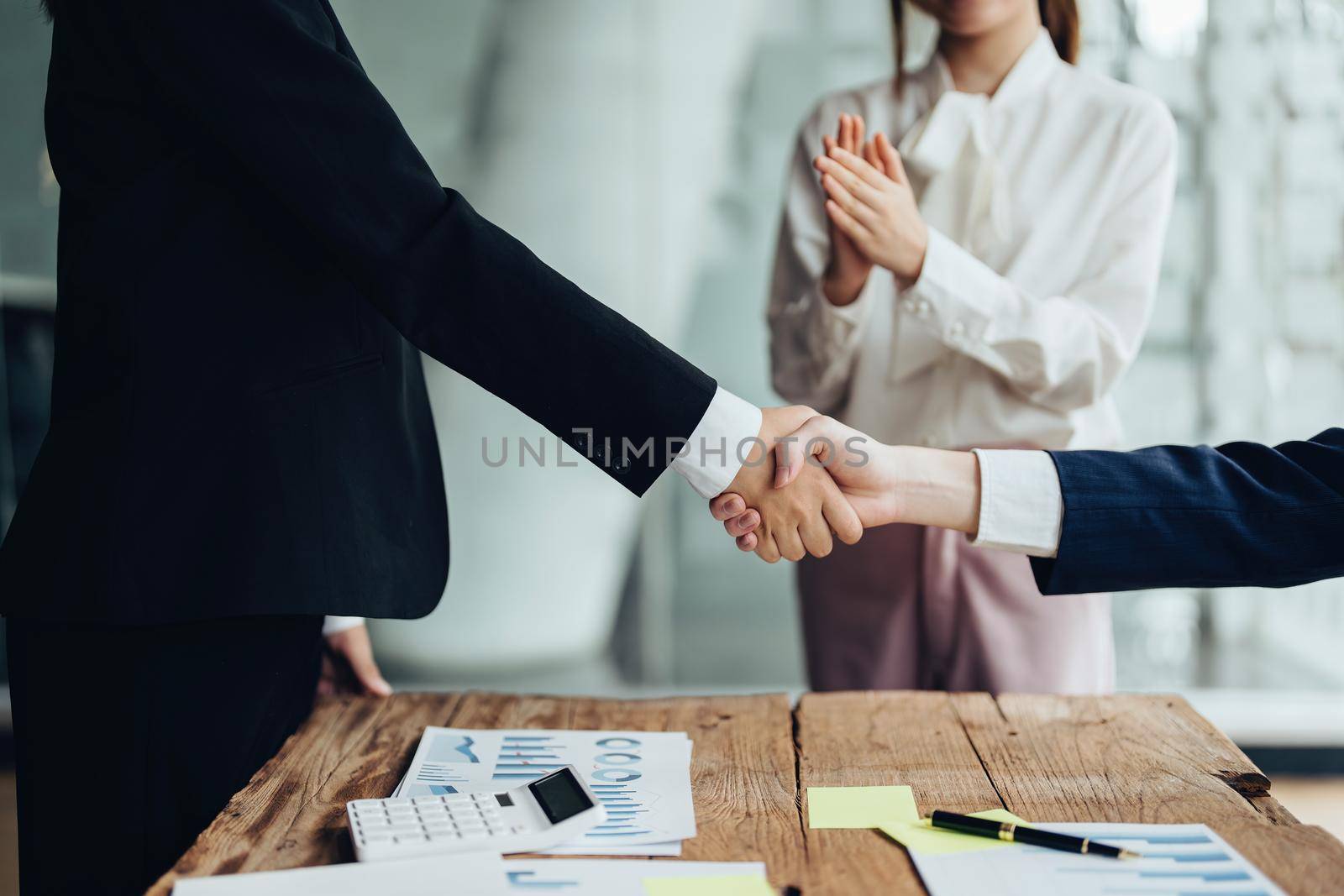 Asian entrepreneurs handshakes to congratulate the agreement between the two companies to enhance investment and financial strength. deal concept by Manastrong