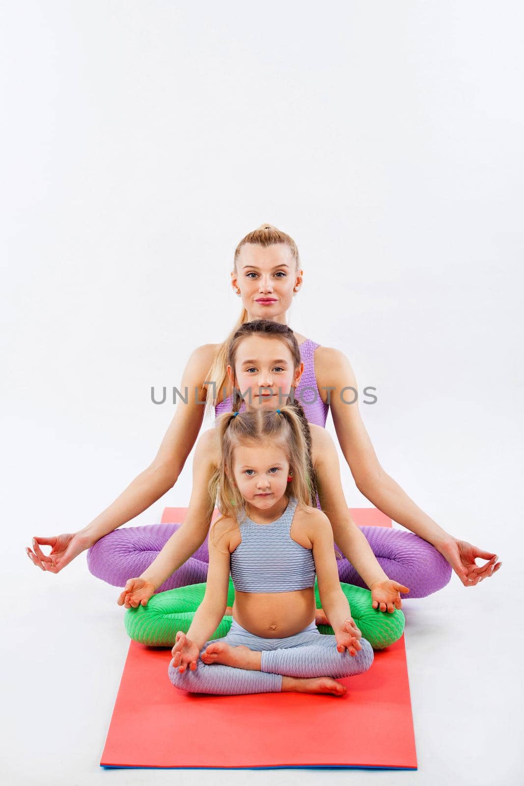 Hatha yoga. Kids fitness . Young mother Instructor and daughters exercise gymnastic together. Isolated on white background. Family look. by MikeOrlov
