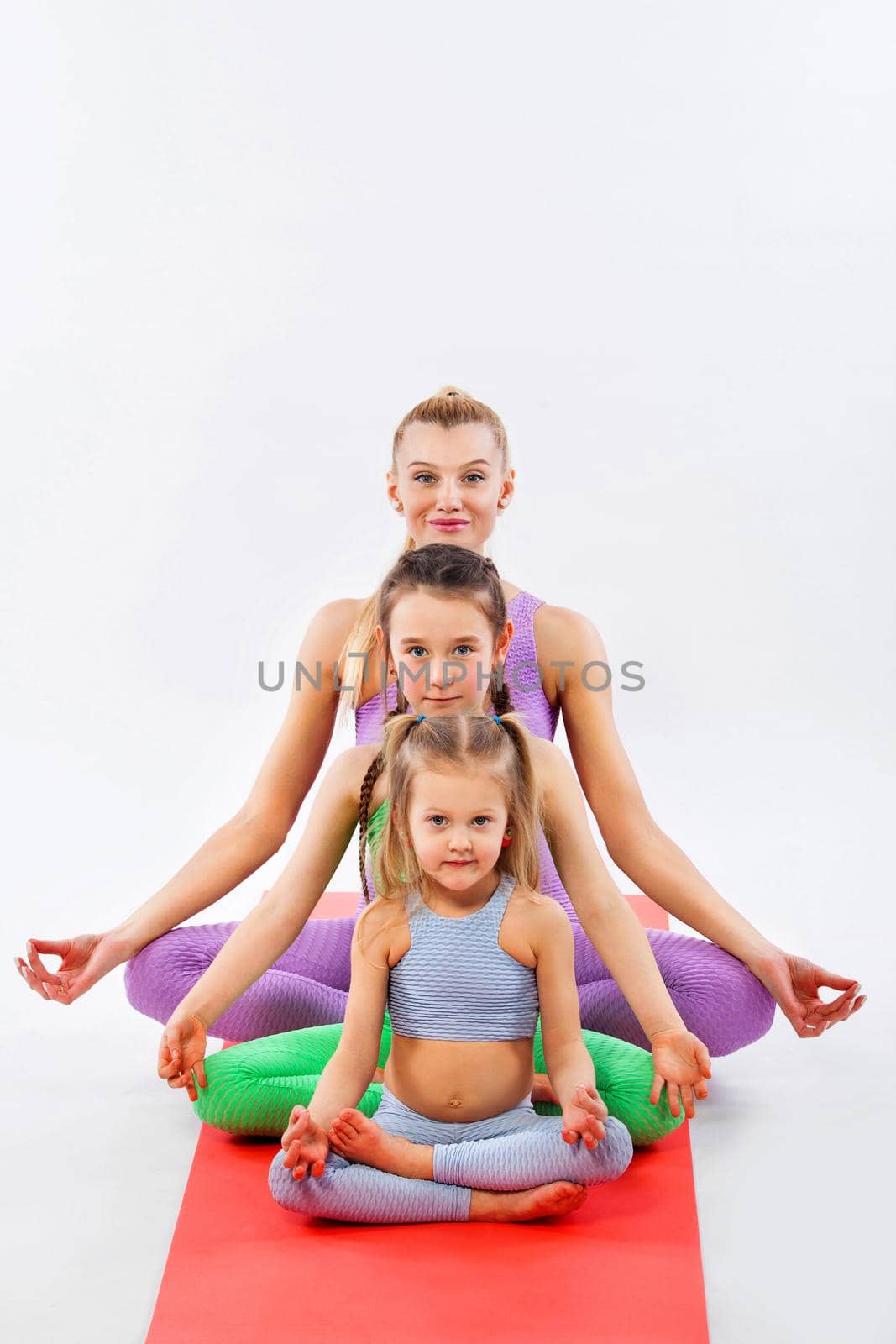 Hatha yoga fitness . Young mother Instructor and daughters exercise gymnastic together. Isolated on white background. Family look. by MikeOrlov