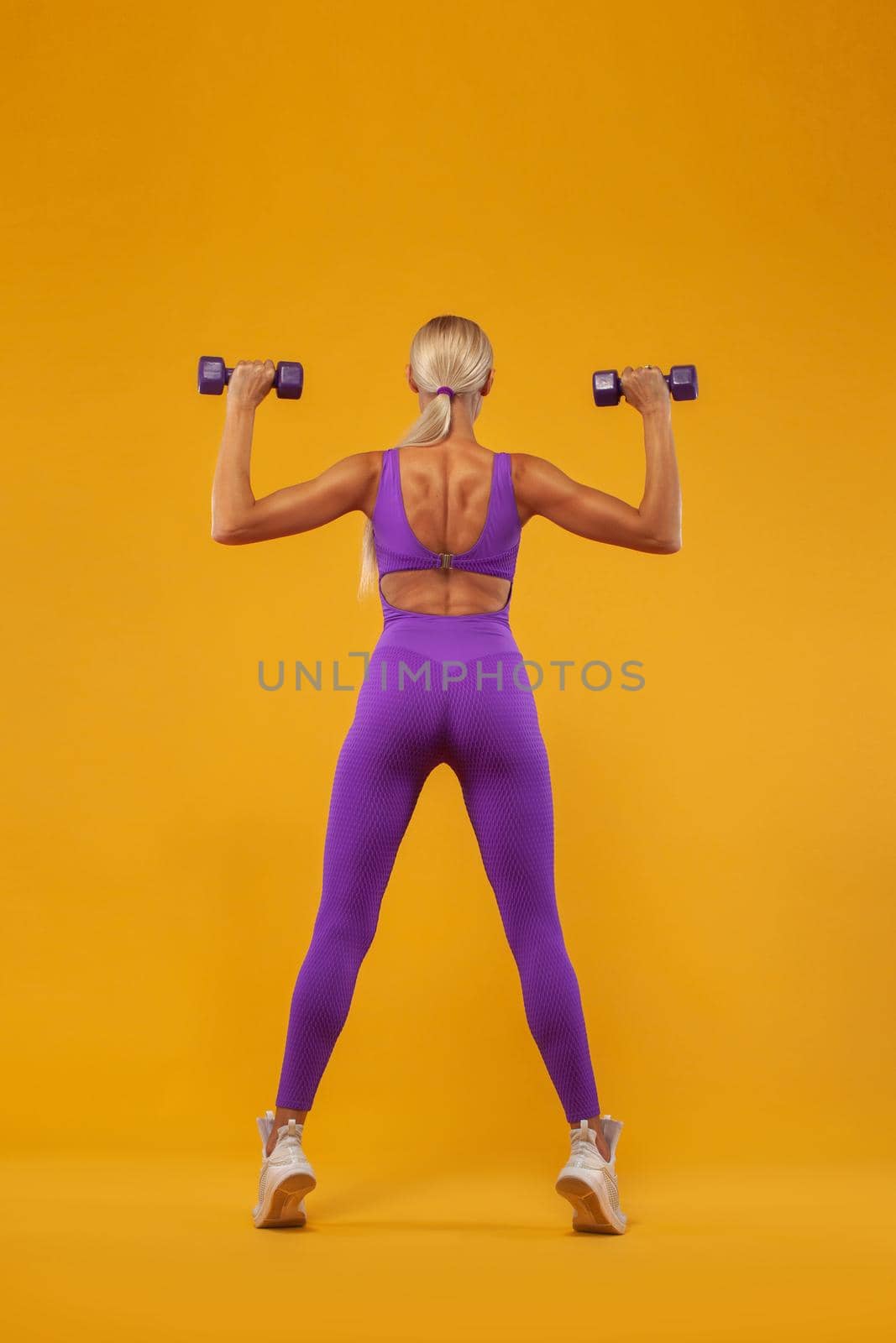 Attractive young fitness woman holding dumbell. Studio shot.