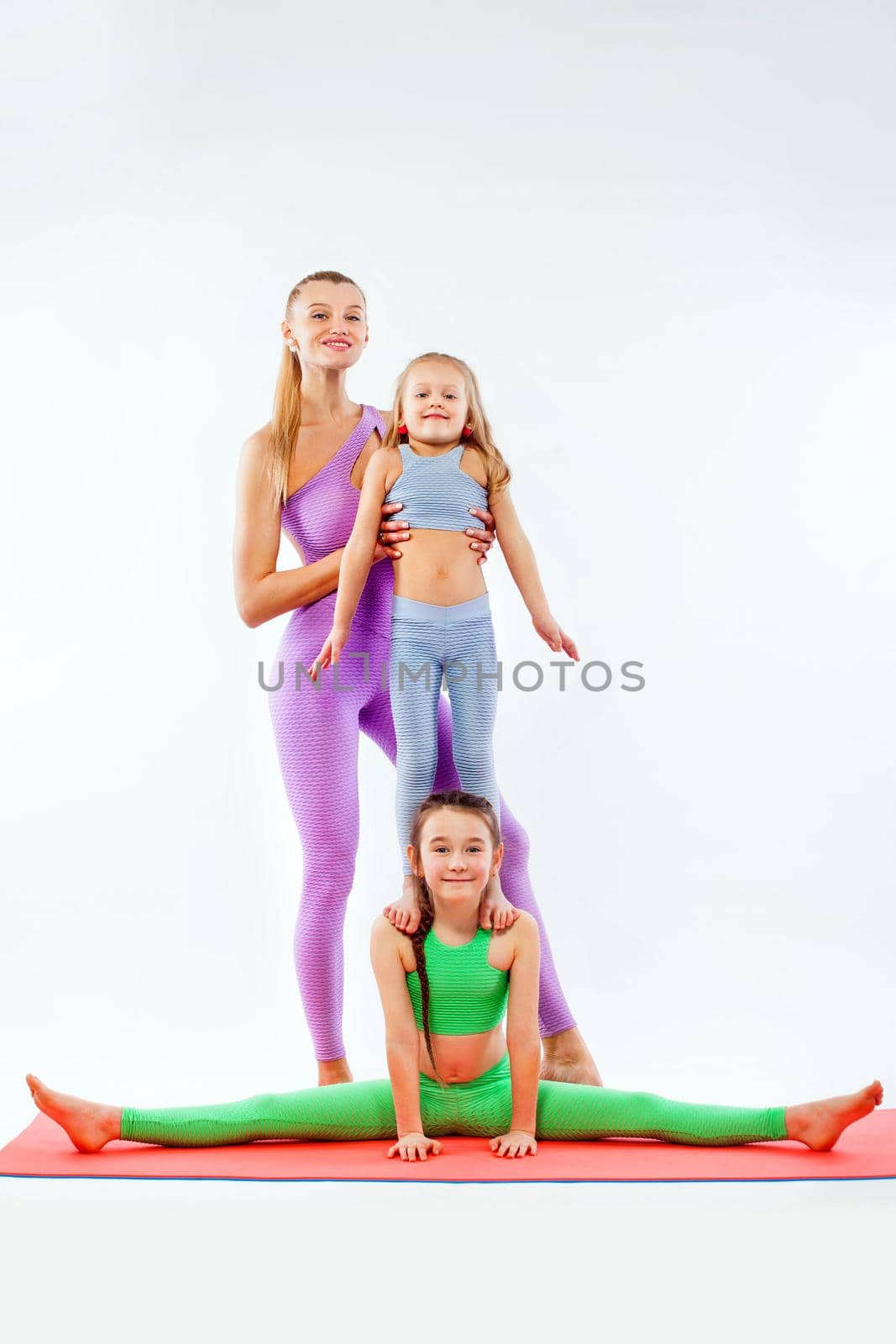 Hatha yoga fitness . Young mother Instructor and daughters exercise gymnastic together. Isolated on white background. Family look. by MikeOrlov