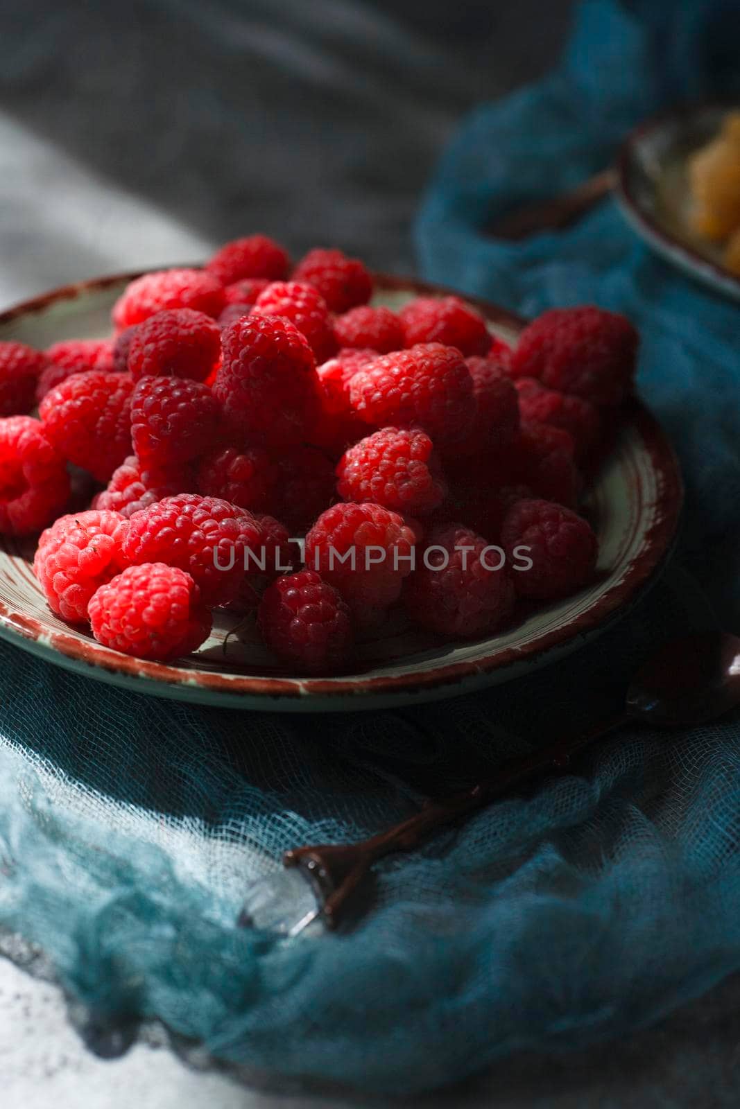 Red raspberry on green plate and green table with blue cloth selective focus.