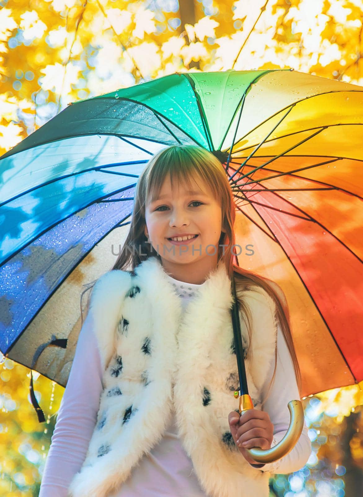 Child under an umbrella in the autumn park. Selective focus. by yanadjana