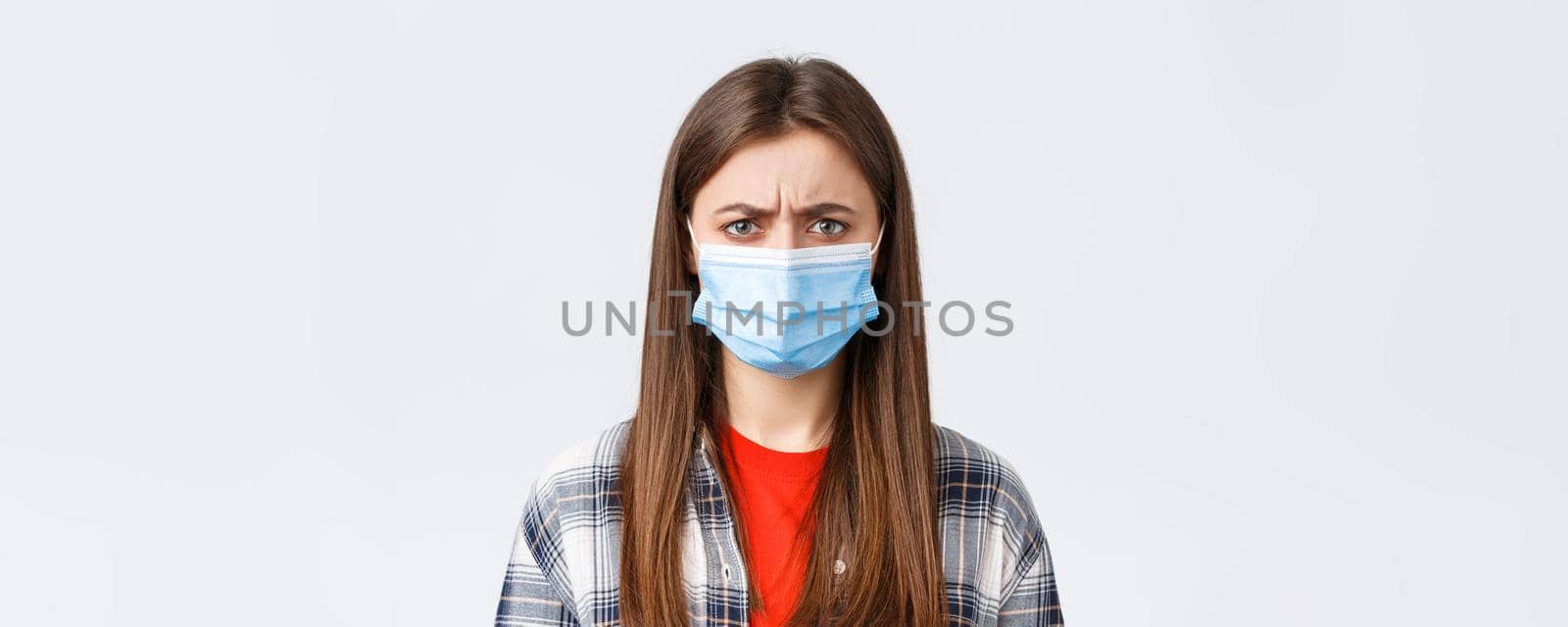 Coronavirus outbreak, leisure on quarantine, social distancing and emotions concept. Close-up of bothered or displeased woman in medical mask, condemn someone, frowning upset.