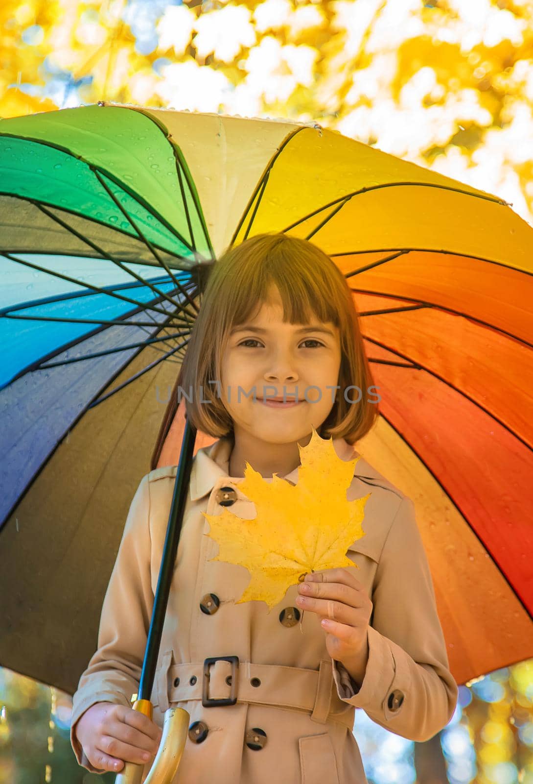 Child under an umbrella in the autumn park. Selective focus.