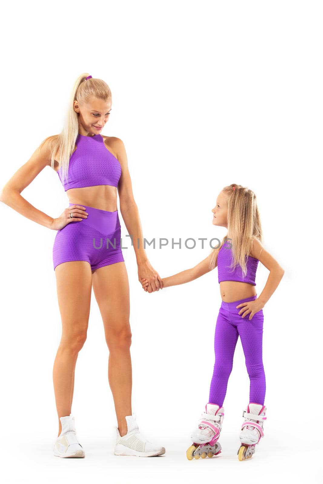 Good looking family, mother and daughter, posing in studio wearing inline roller skates.