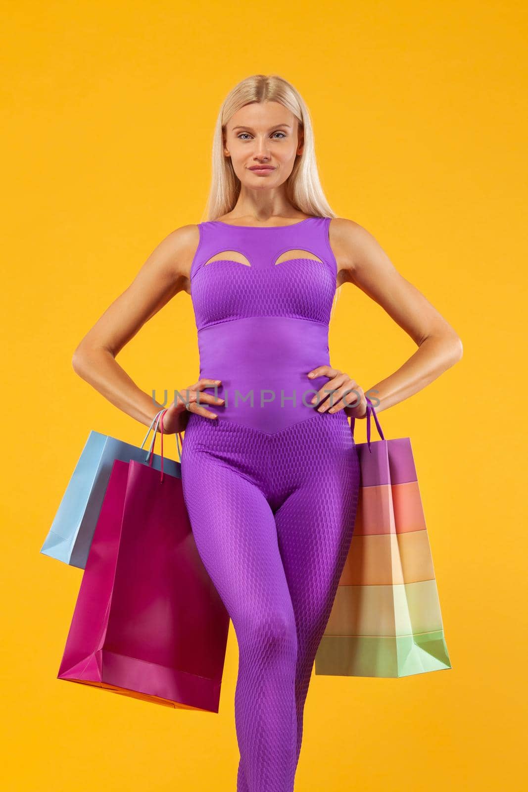 Black friday sale concept for sport shops. Shopping woman athlete holding color bag isolated on yellow background in holiday by MikeOrlov