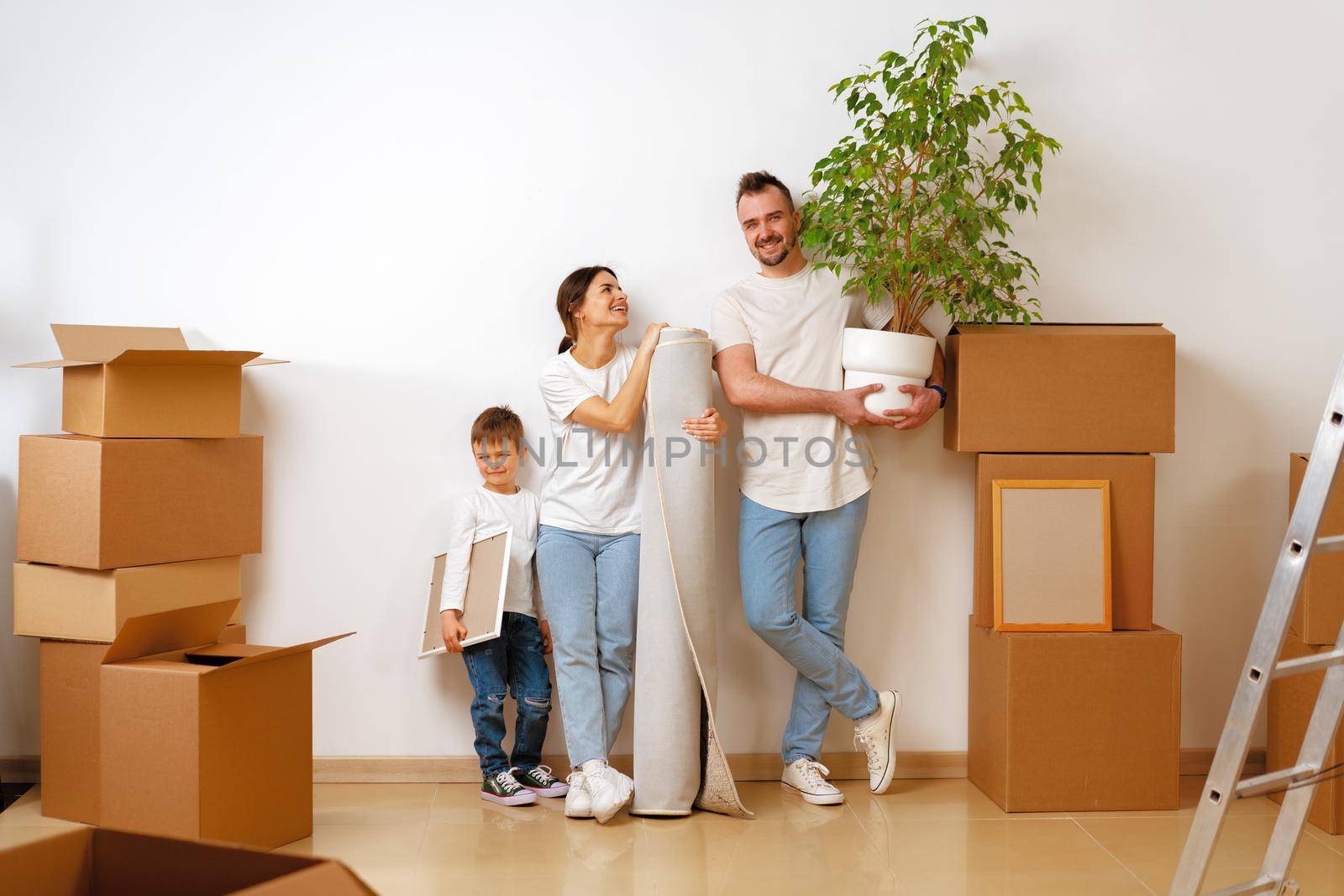 Portrait of happy family with cardboard boxes in new house at moving day by Fabrikasimf