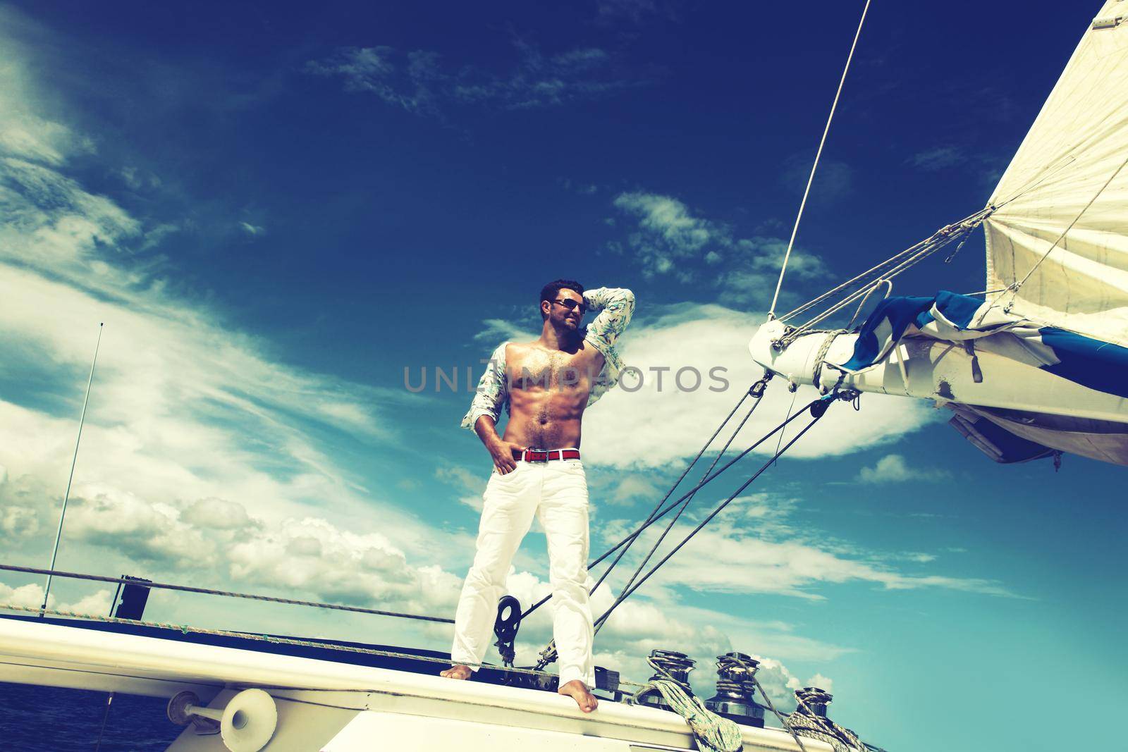Young man sailing his boat on the open ocean by Taut