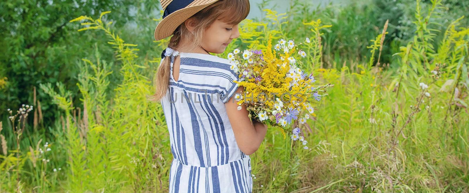 girl holding wildflowers in the hands of a child. Selective focus.