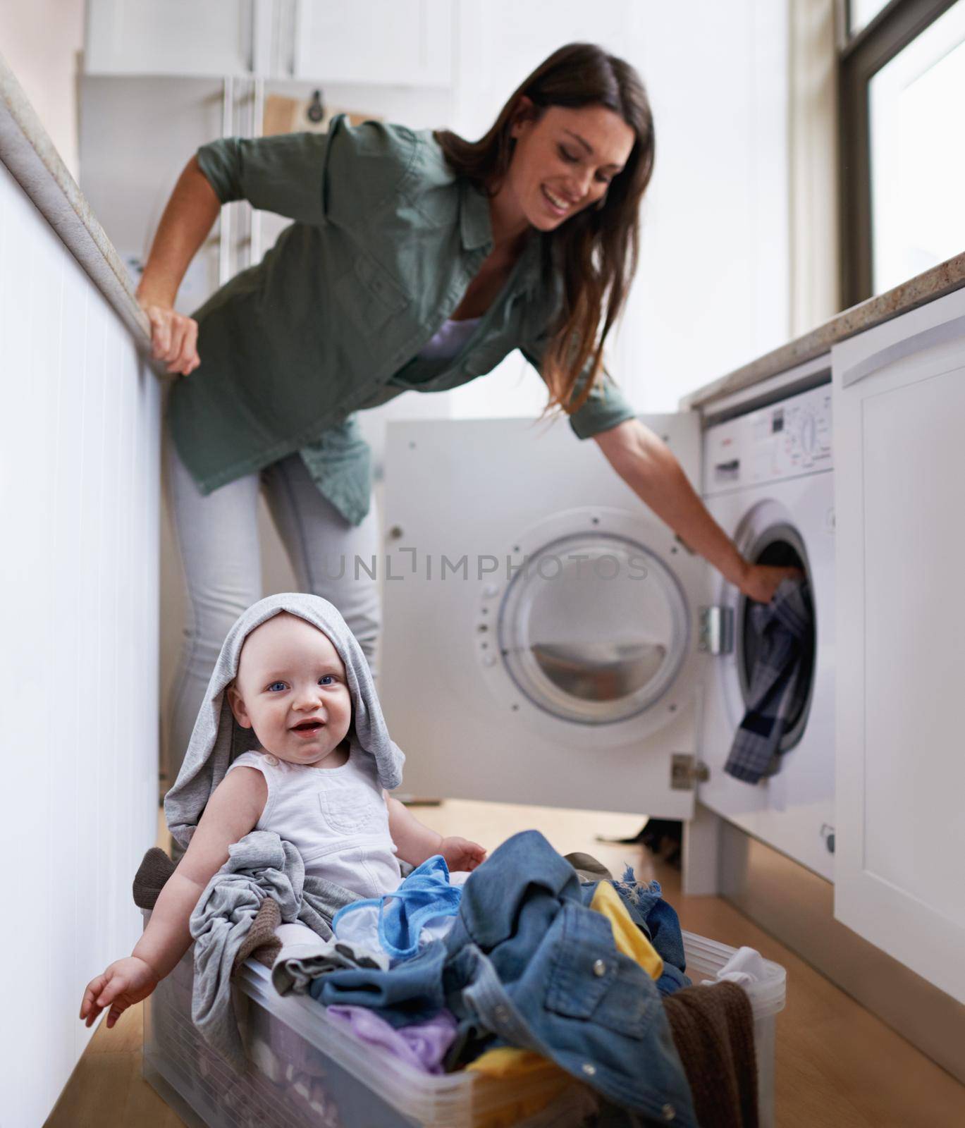 A mother doing laundry while keeping an eye on her baby.