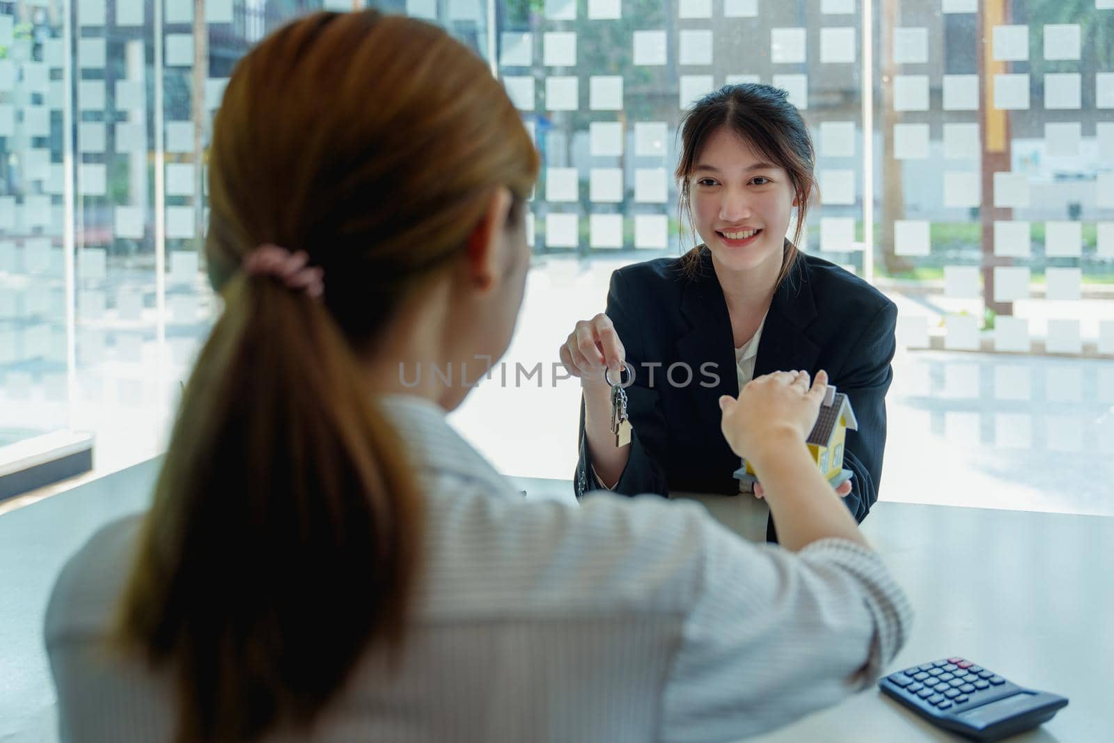 Accountant, businessman, real estate agent, Asian business woman handing keys to customers along with house after customers to sign.