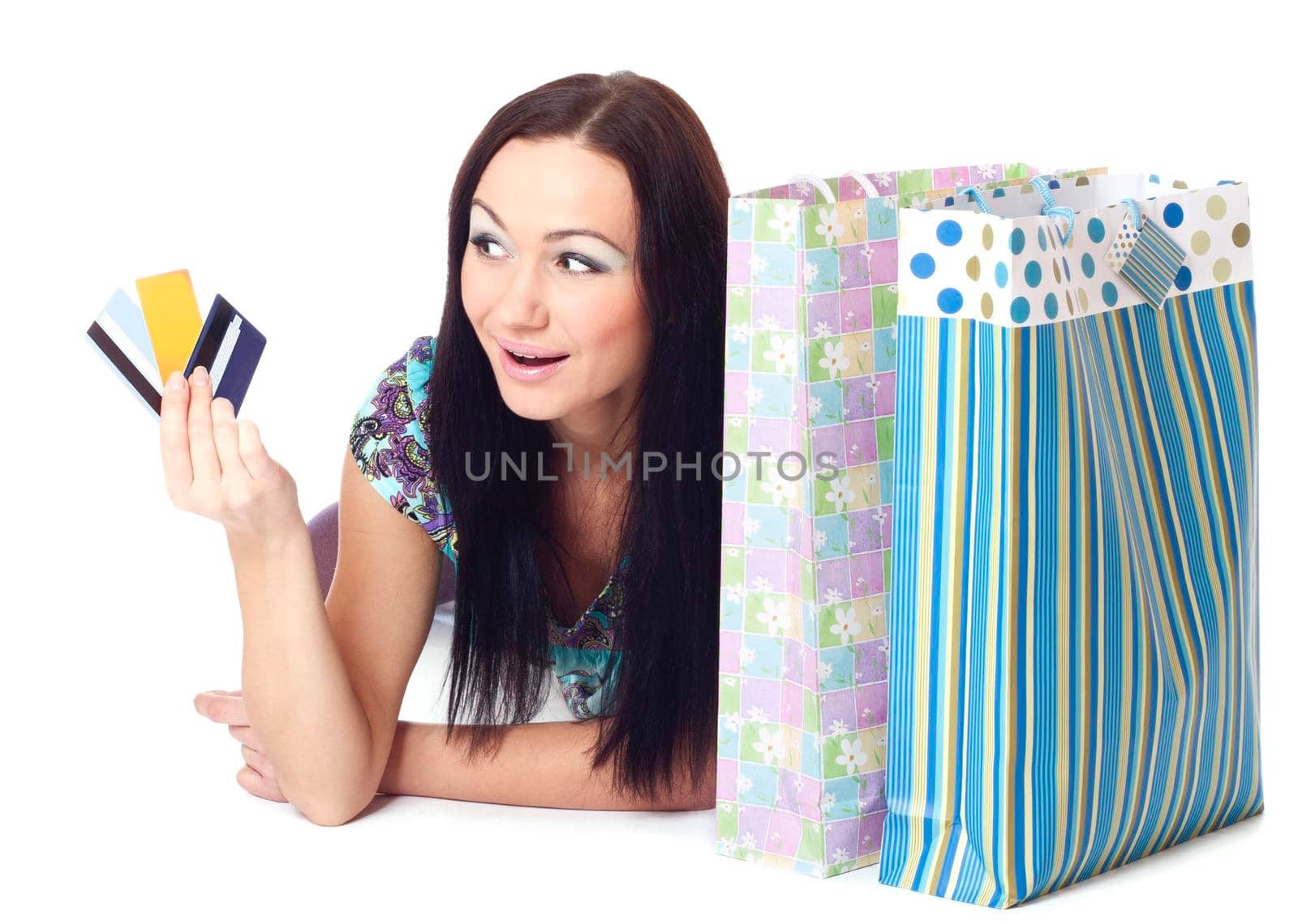 Beautiful surprised woman holding credit cards and bags. Isolated on white.