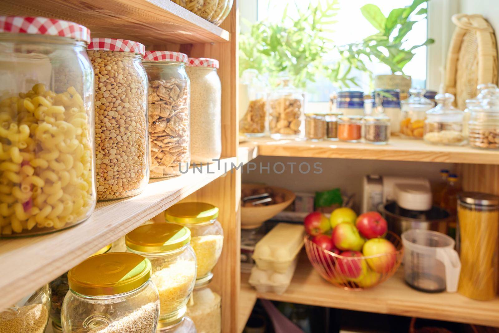 Storage of food in the kitchen in the pantry. Cereals, spices, pasta, nuts, flour in jars and containers, kitchen utensils. Cooking at home, stocking food, household