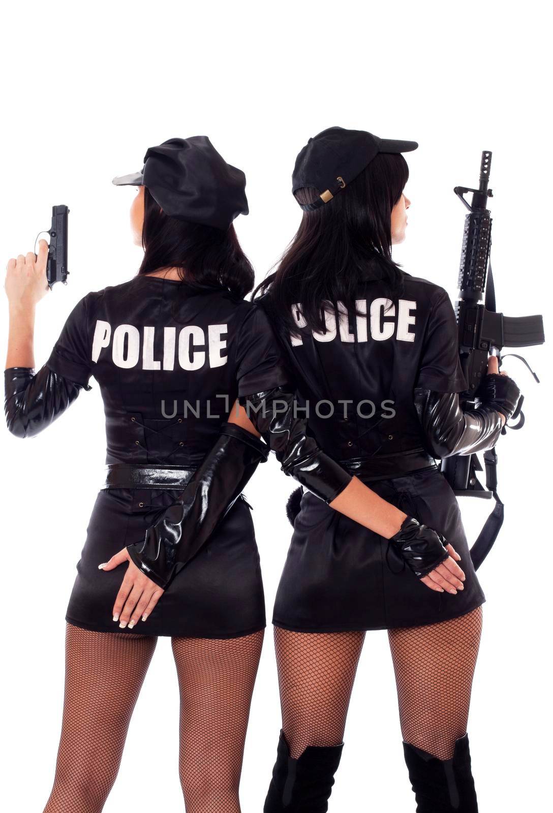 Portret of two beautiful sexy policewomen with handcuffs in a black uniform that aiming a submachine gun. Iisolated on white.