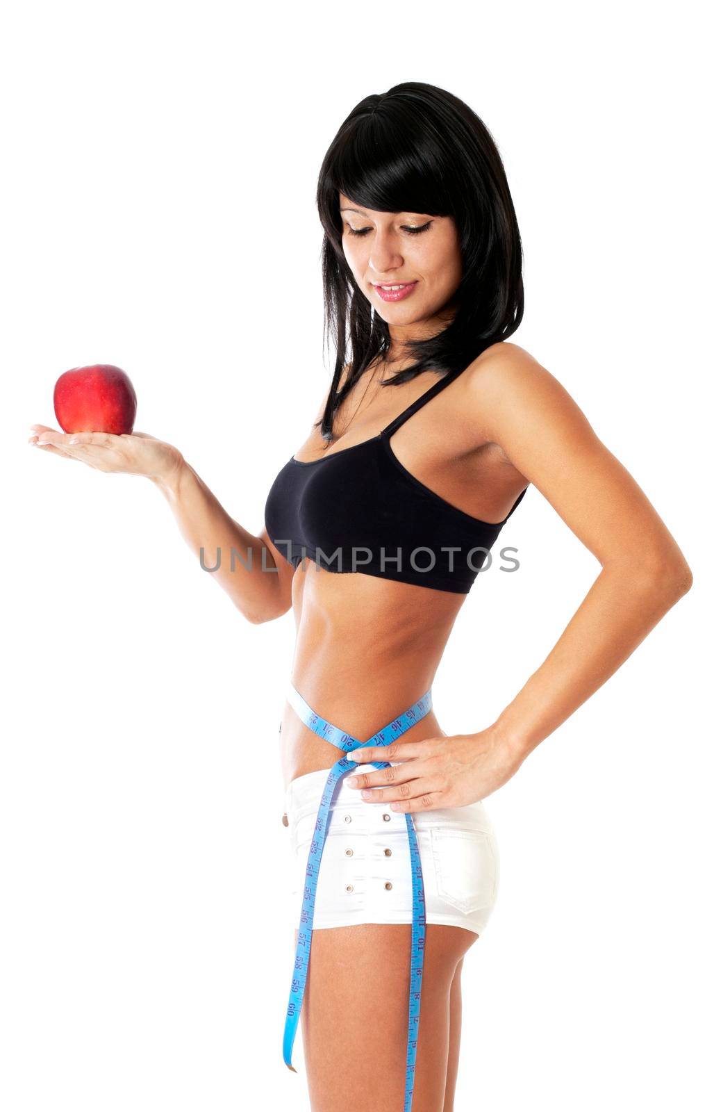 Pretty brunette girl holding apple and showing with a measuring tape around her waist how much centimeters she has already lost. Isolated on white.