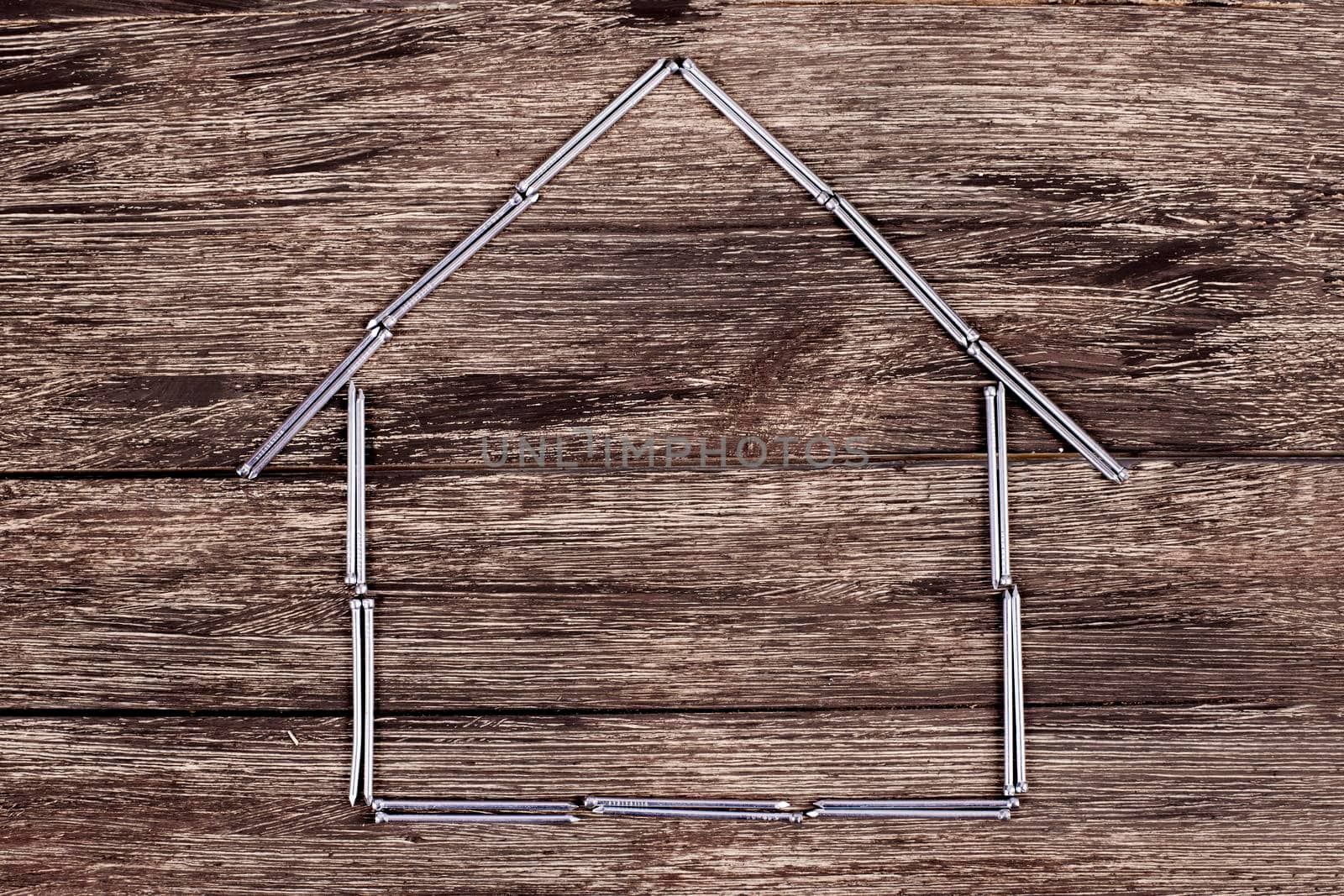 House from nails on wooden background by Jyliana