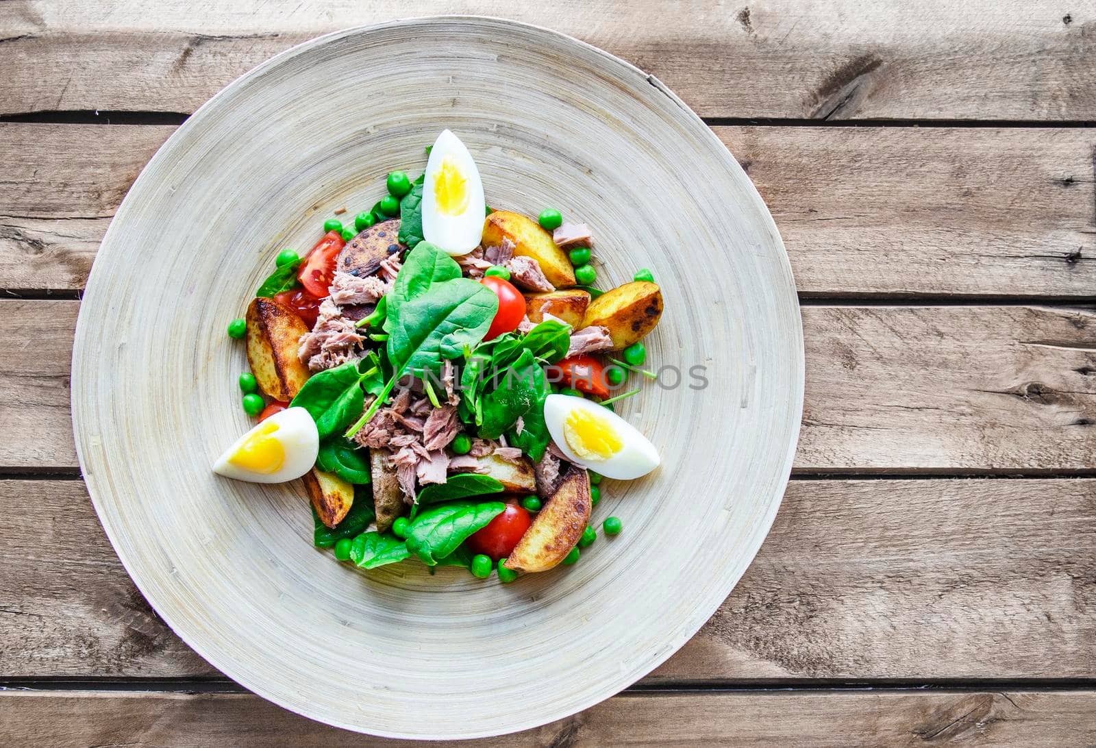 Tuna salad with lettuce, eggs and tomatoes on wooden plate