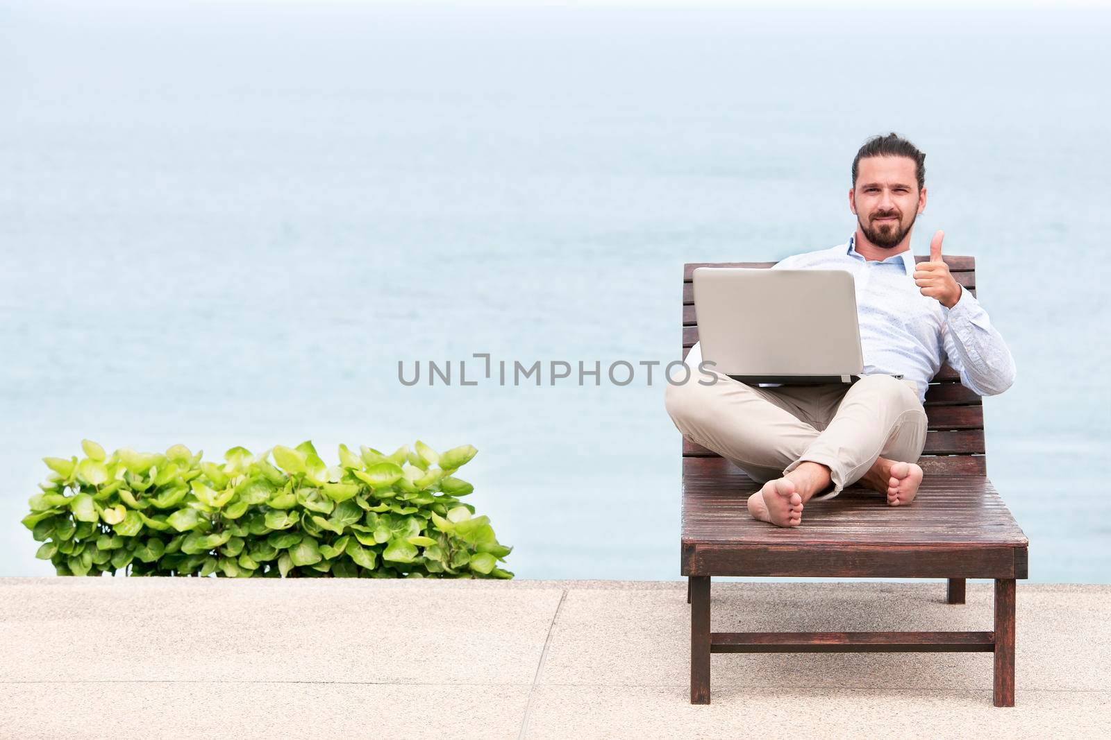 Businessman freelance on beach with laptop by Jyliana