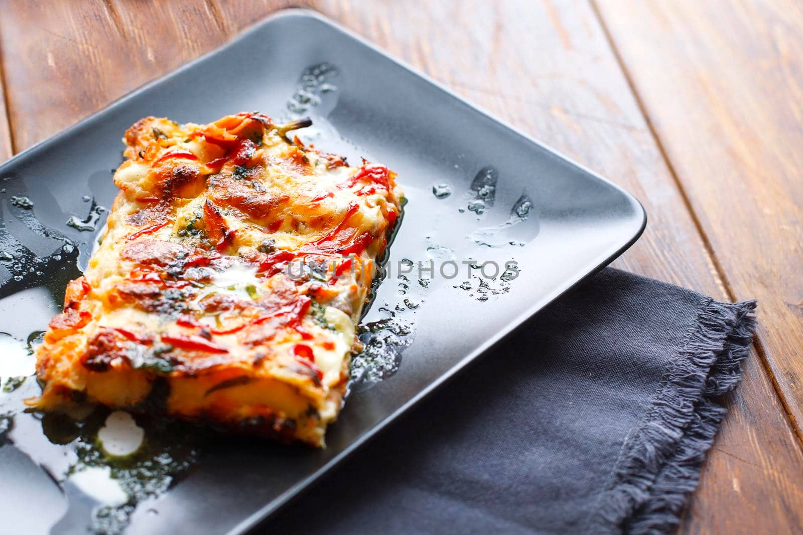 traditional italian lasagna with minced beef bolognese sauce, black modern plate, top view