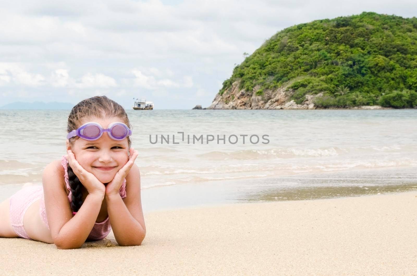 Happy little girl lying on the sand on the beach Female preschooler kid by Jyliana