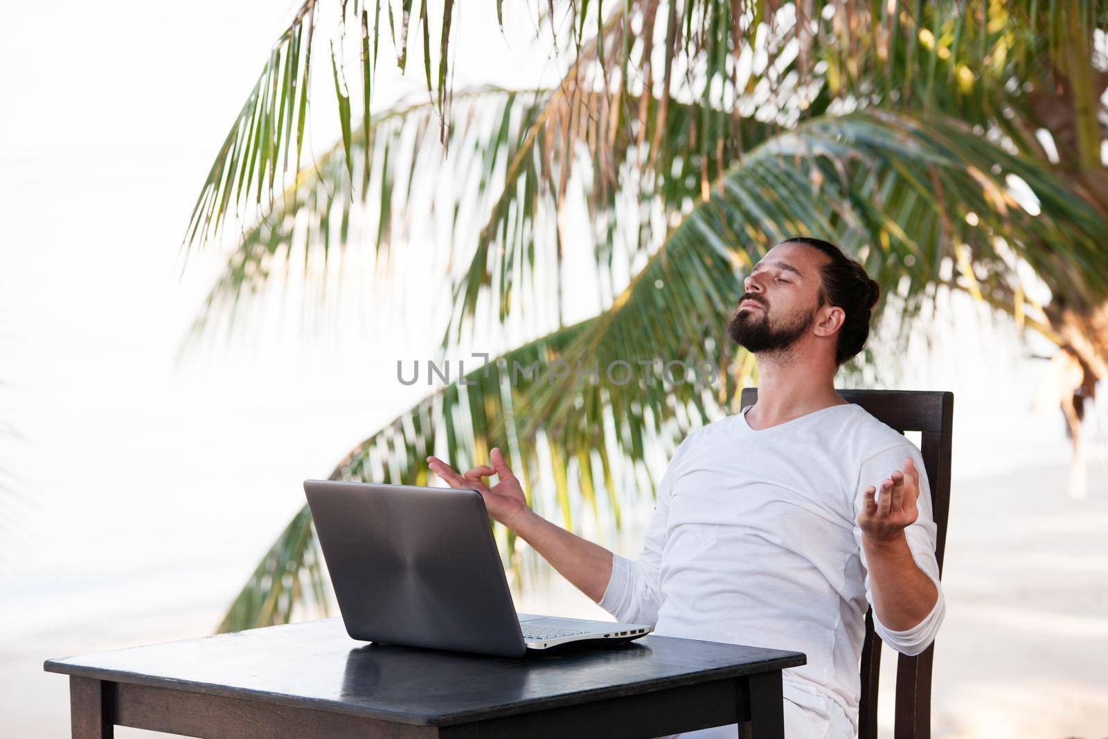 telecommuting, businessman relaxing on the beach and doing yoga with laptop and palm, freelancer workplace, dream job