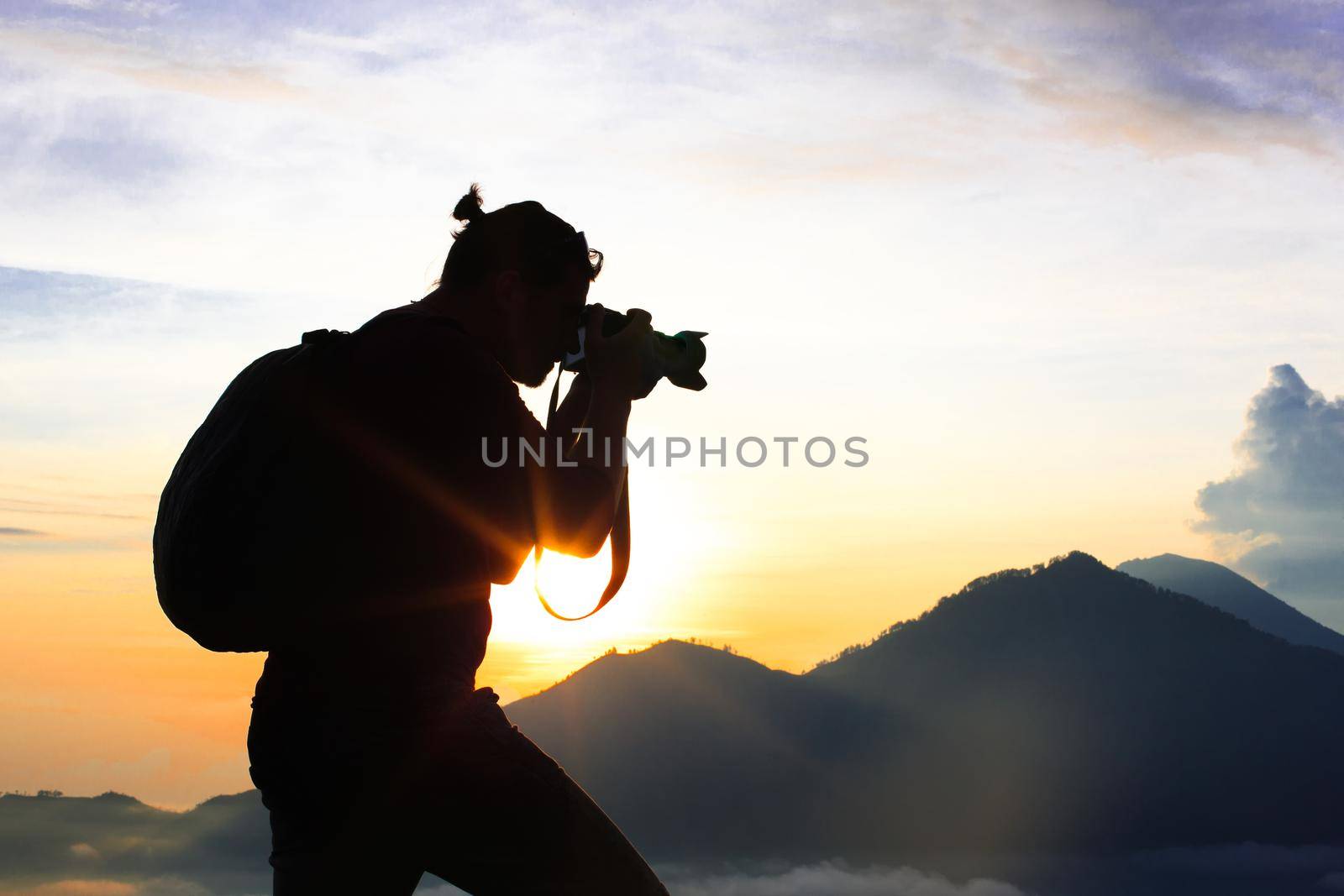 Photographer Hiker walking along, takes pictures and meets sunrise on the mountain