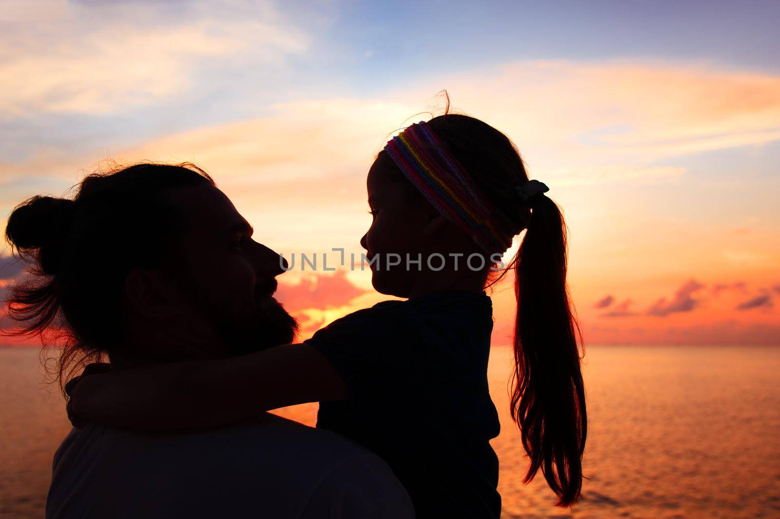 Silhouette of father and daughter on the beach at dusk. Sunset