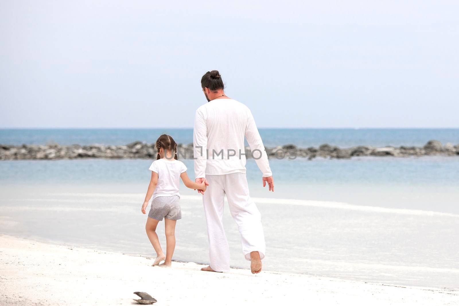 Adorable little girl holding her father hand. Healthy father and daughter playing together at the beach carefree happy fun smiling lifestyle