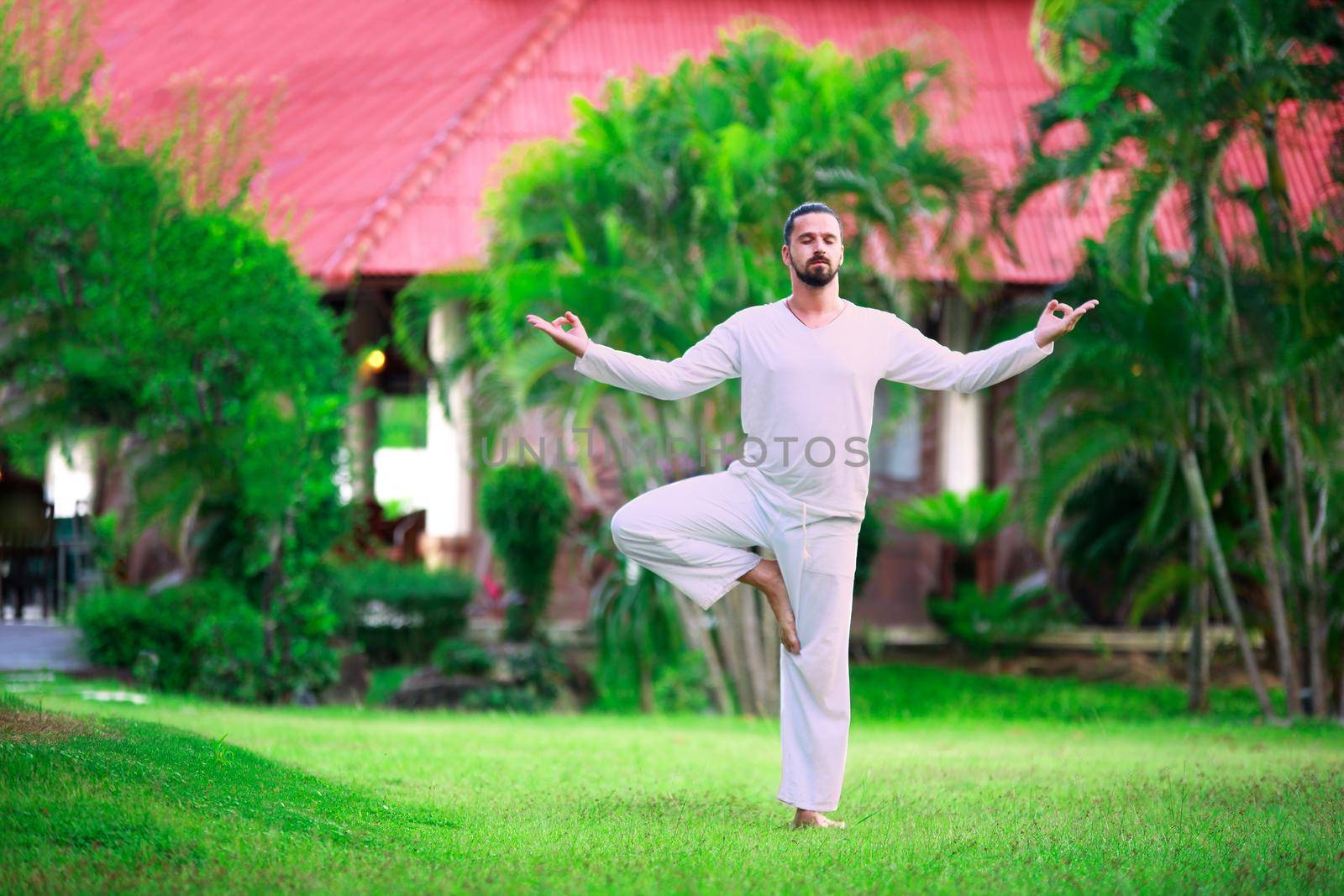 Man wearing white doing yoga in tropic jungle