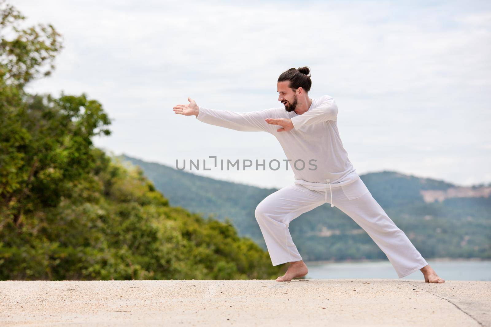 Kickboxer or muay thai fighter Man in white kimono training karate or Wushu on mountain background.