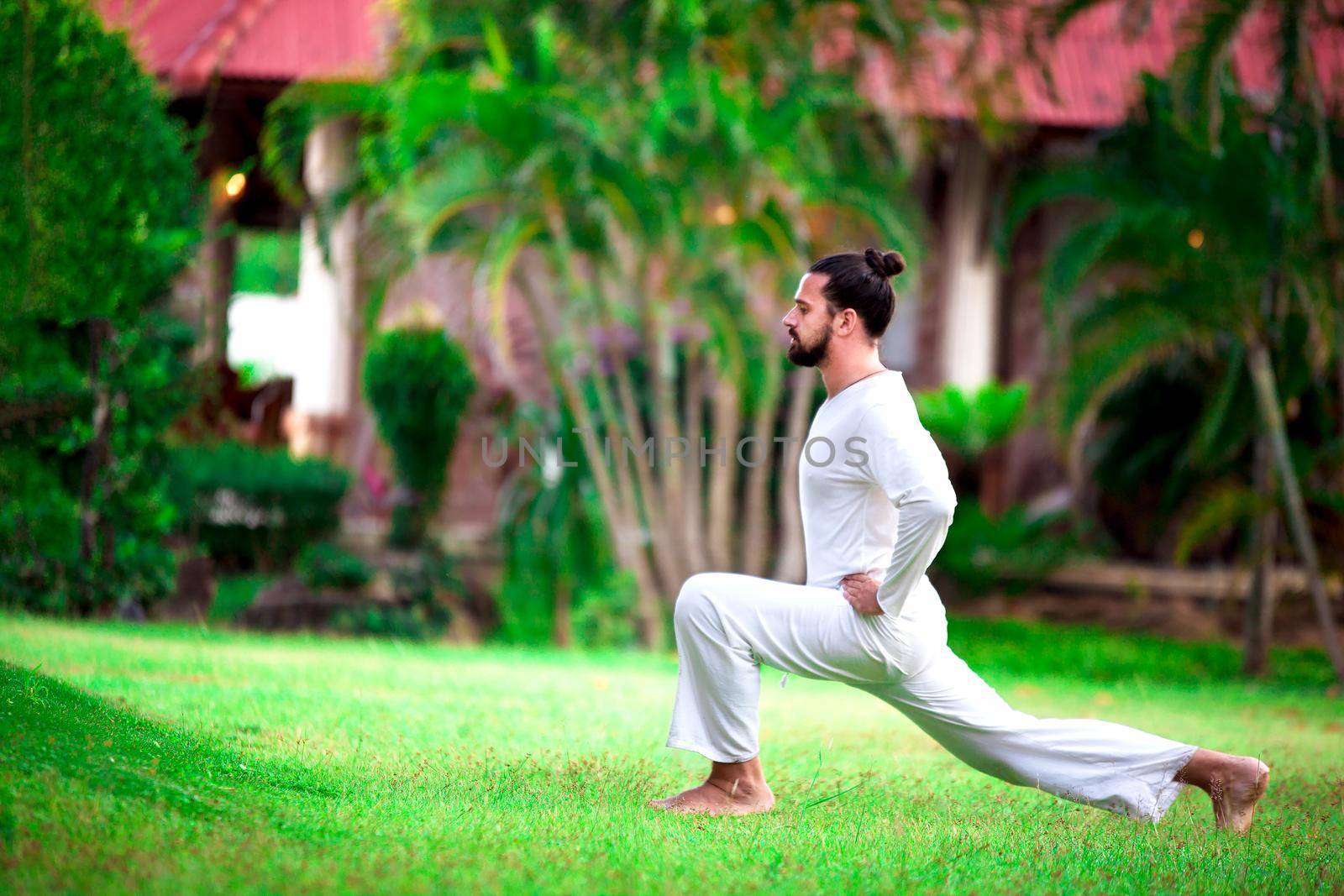 Man wearing white doing yoga in tropic jungle