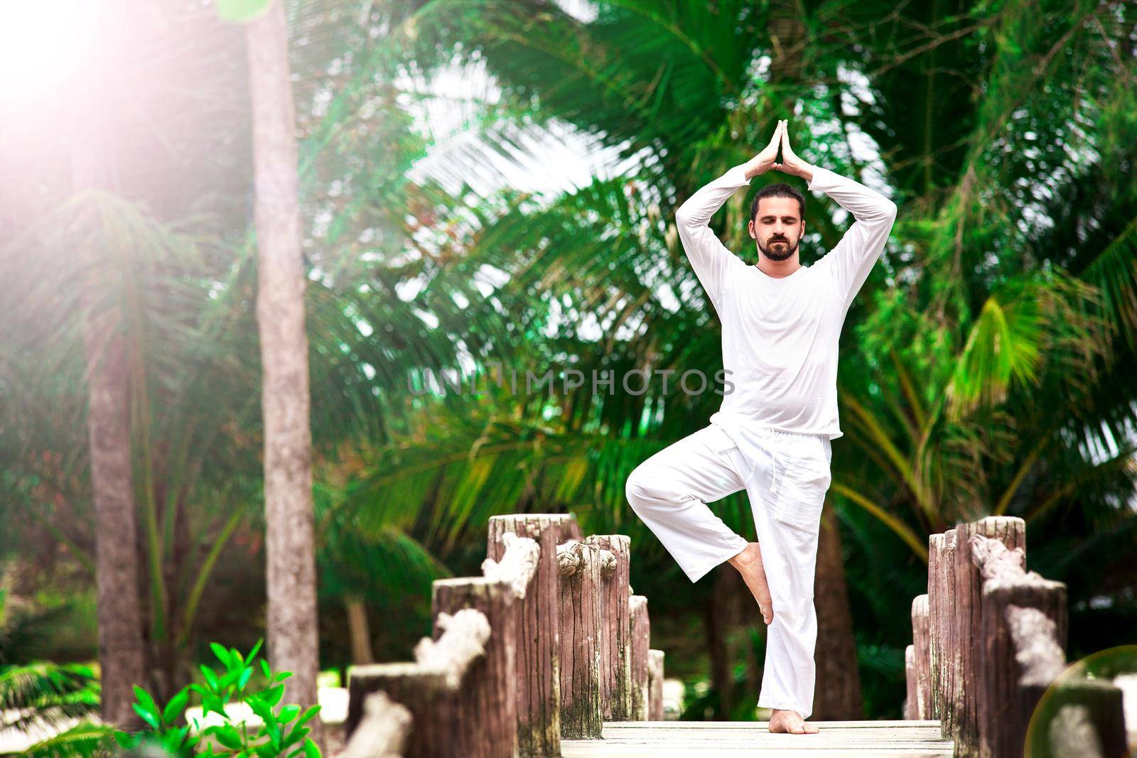 man doing yoga in tropic jungle bridge by Jyliana