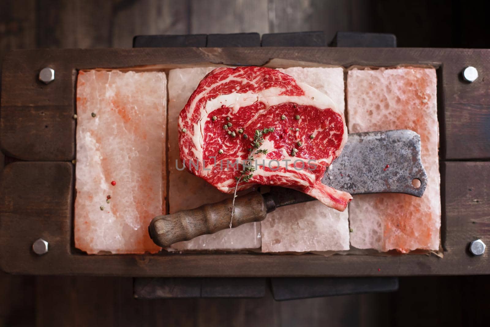 Bone In Rib Eye row Steak on pieces of salt on a wooden board. Stock image