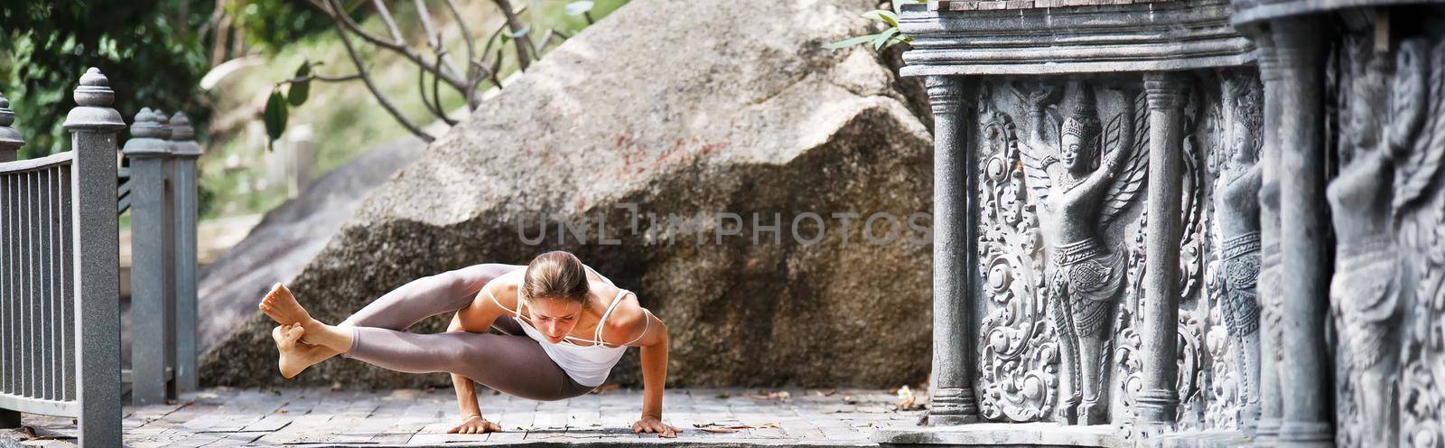 Young woman doing yoga in abandoned temple on wooden platform. Practicing in Thailand