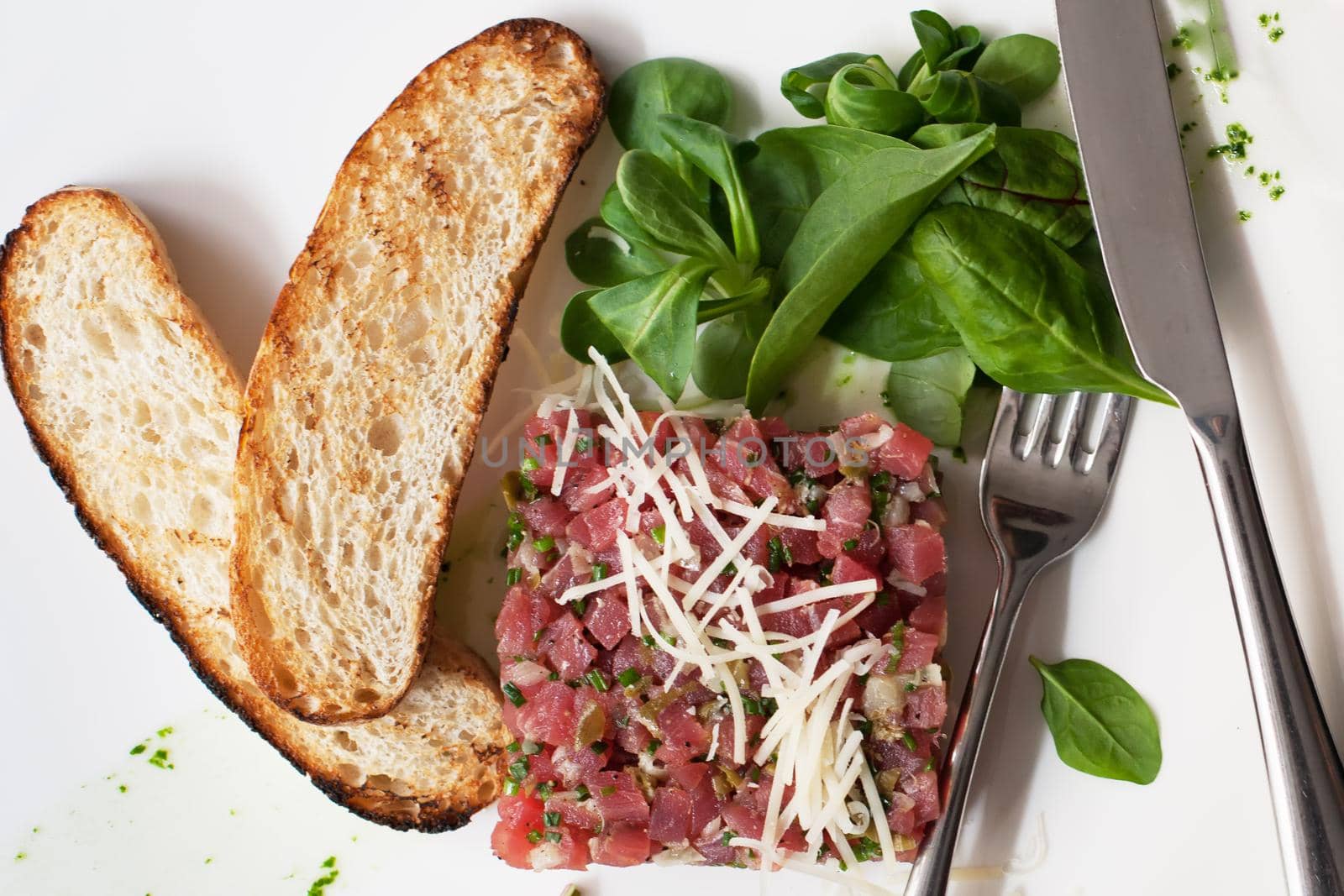 Tartare of beef with spinach on a white plate.