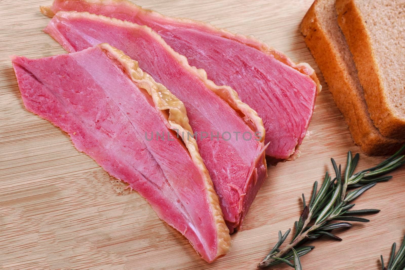 Homemade ham meat sliced and bread on wooden desk.