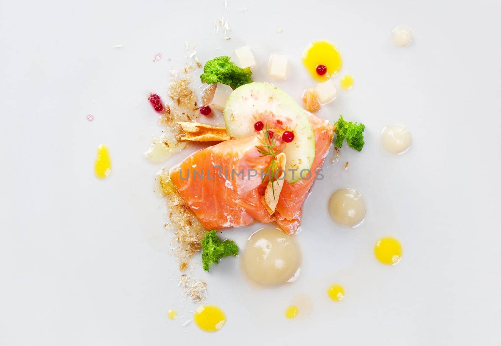 Molecular modern cuisine red fish in a dish with beautiful garnish close up. Isolated