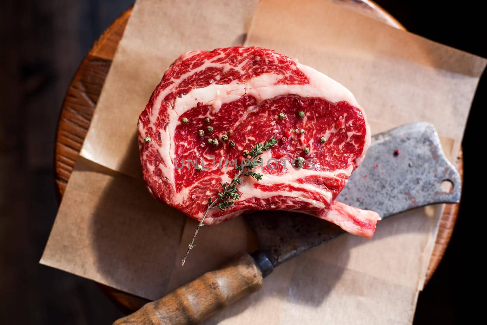 Bone In Rib Eye row Steak on pieces of salt on a wooden board. Stock image