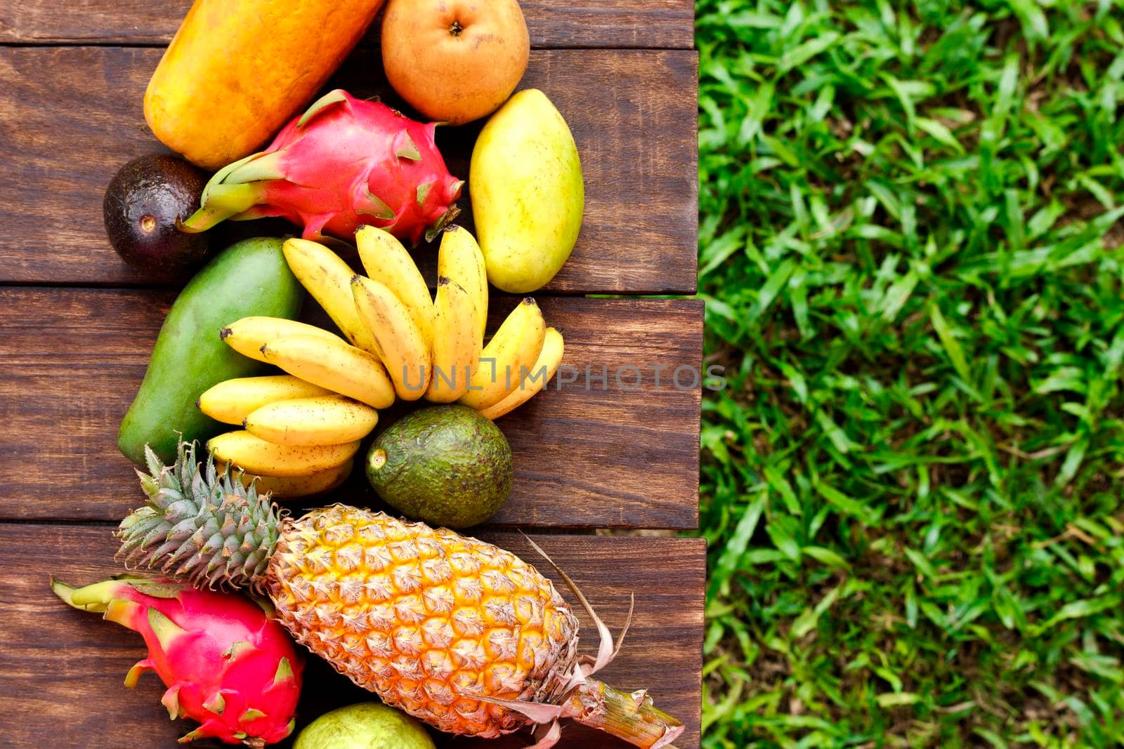 Fresh fruits. Mixed exotic fruits on wood background. Healthy eating, dieting. Top view with grass copy space